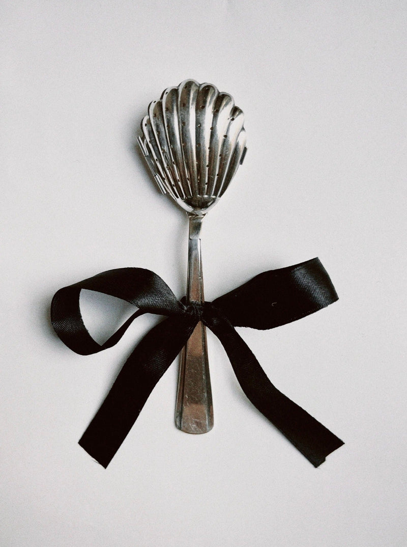 Silver shell-shaped tea infuser with black ribbon bow