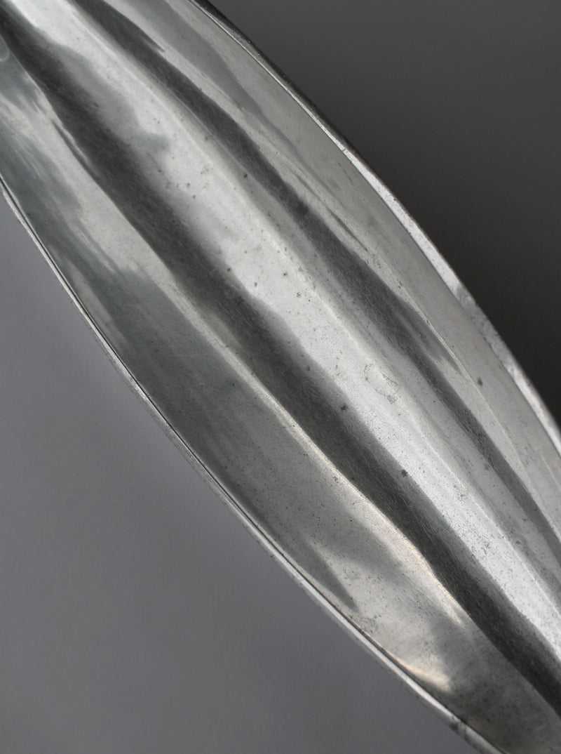 Close-up detail of polished aluminum bowl showing reflective ridged surface