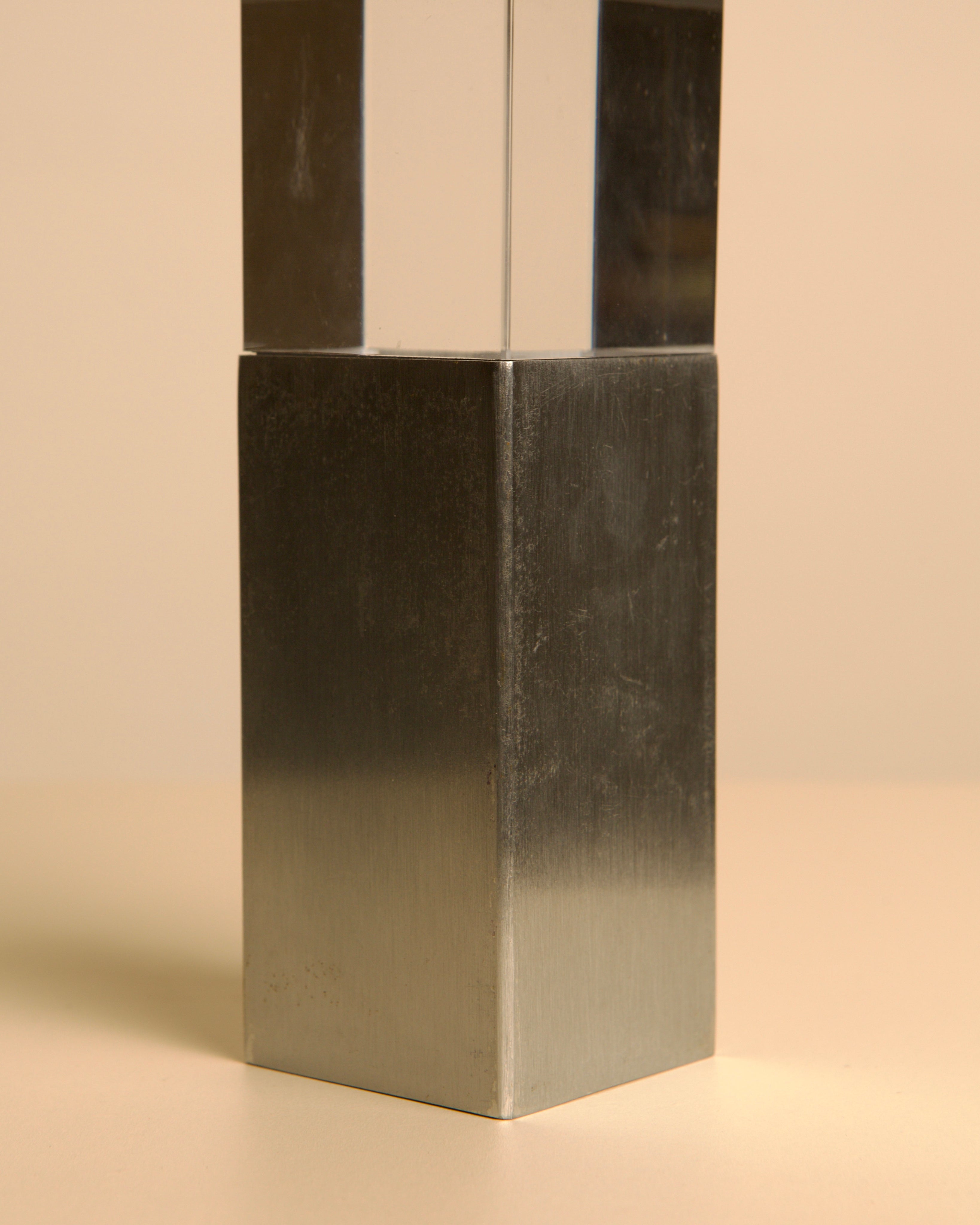 The Treaptyque Italian Sculpture in Metal and Plexiglass 70's features a metallic rectangular prism with a clear plexiglass top, standing upright on beige—evoking iconic 1970s Italian design.