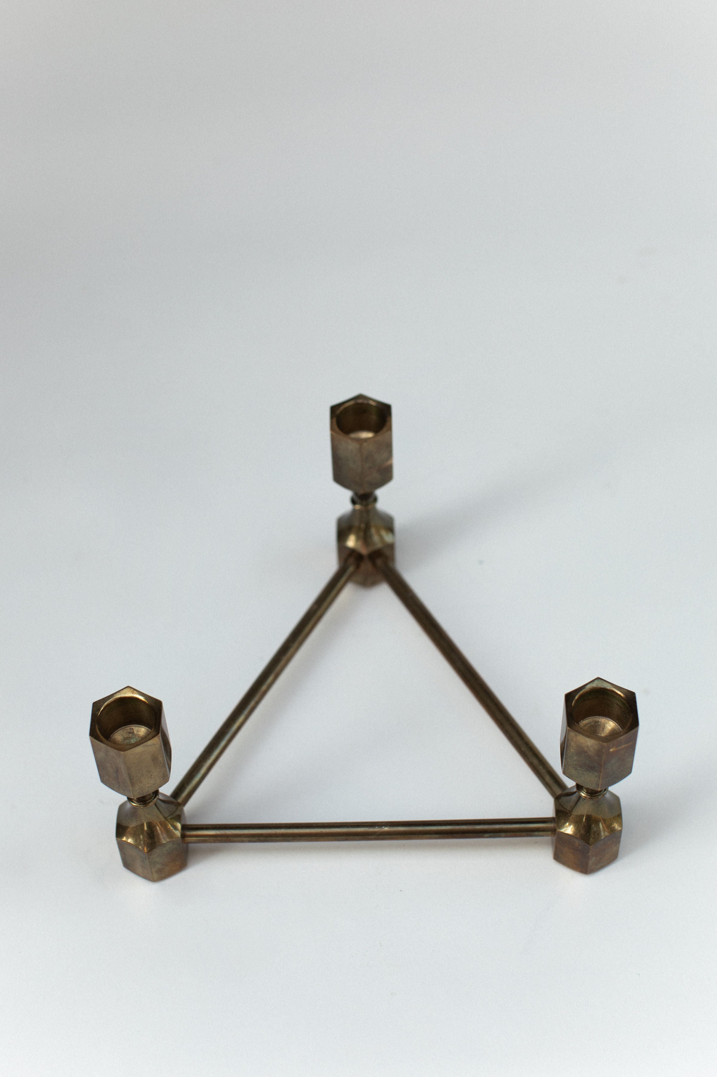 Triangular brass candle holder with geometric hexagonal cups