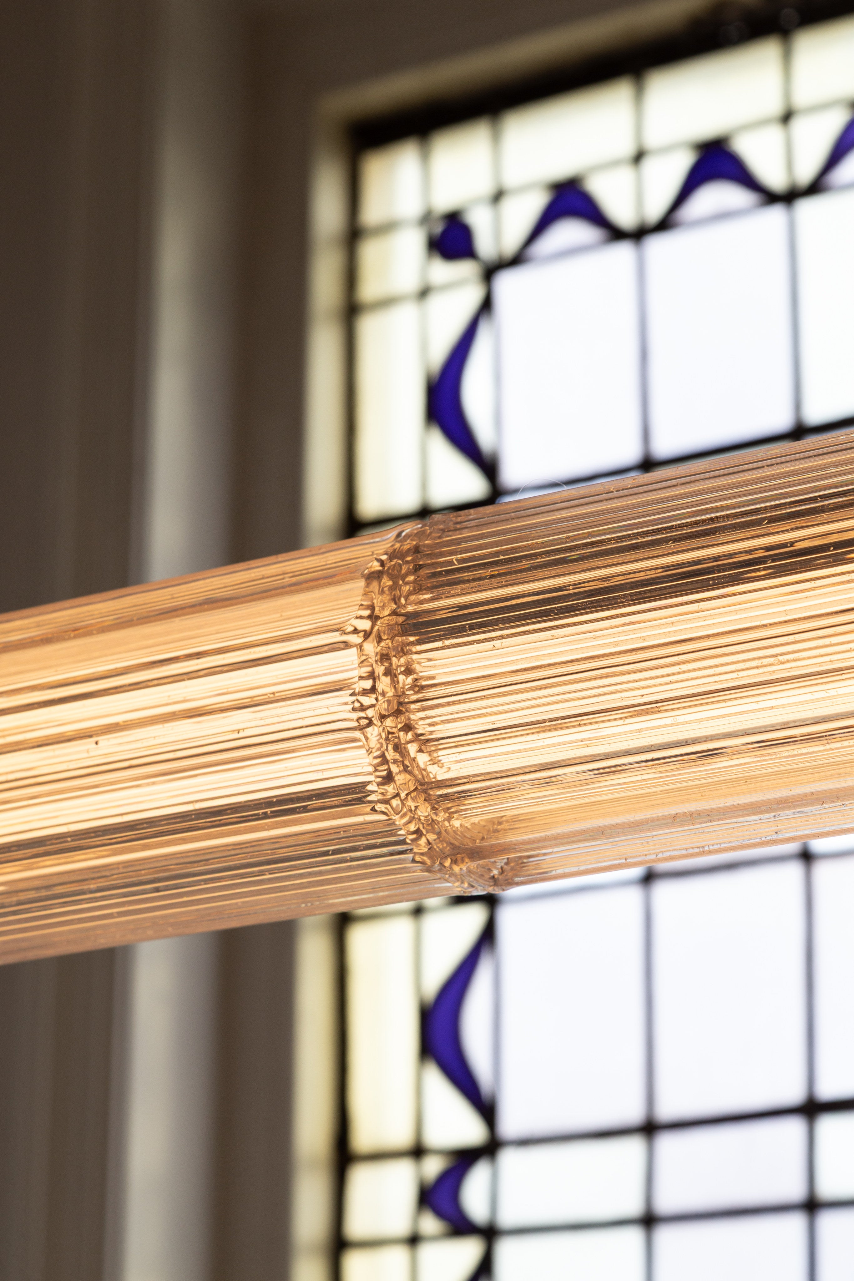 Former" Aperture 200 — close-up of glass pendant light against stained glass
