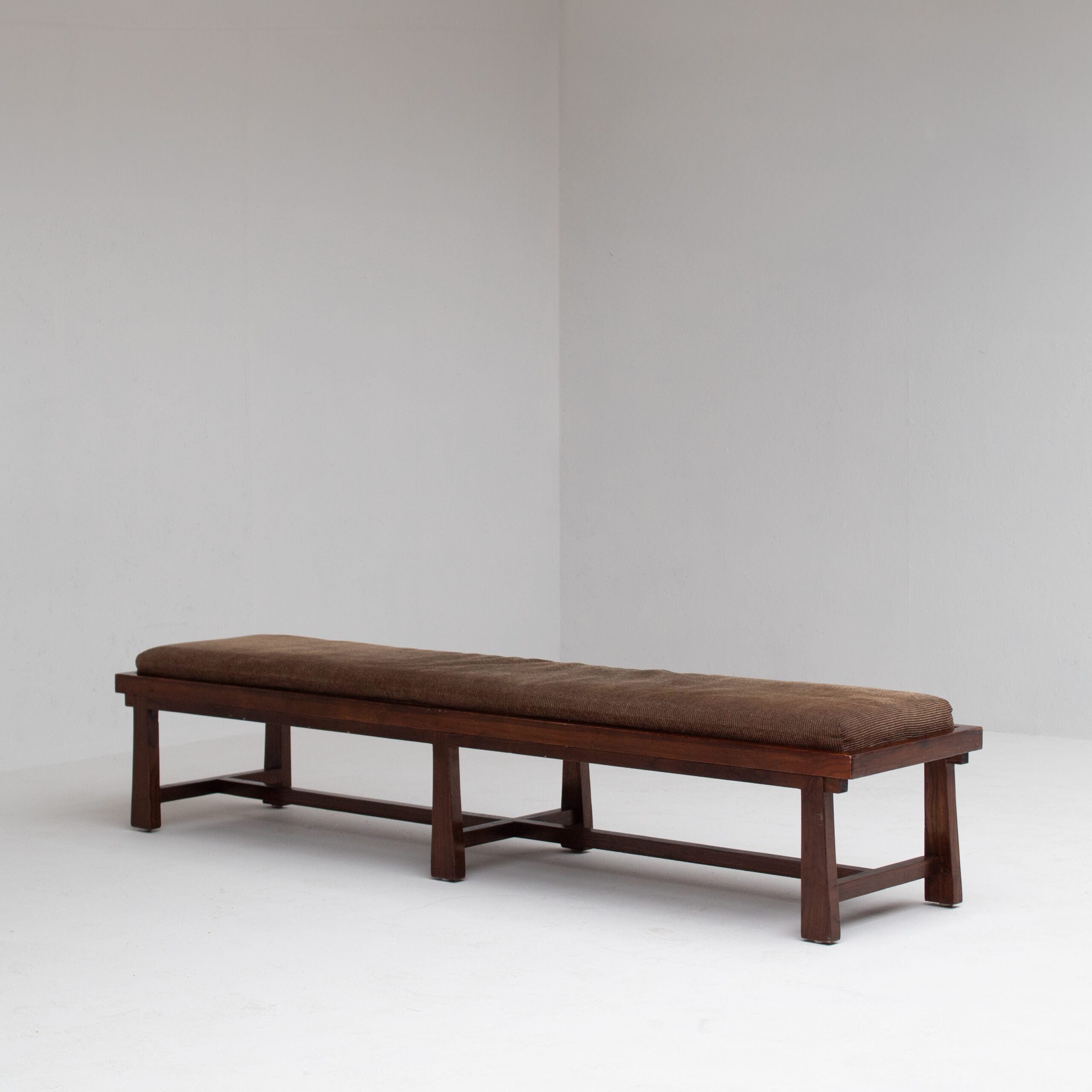 Rustique Bench in Wood with Cushion — angled view in minimalist setting