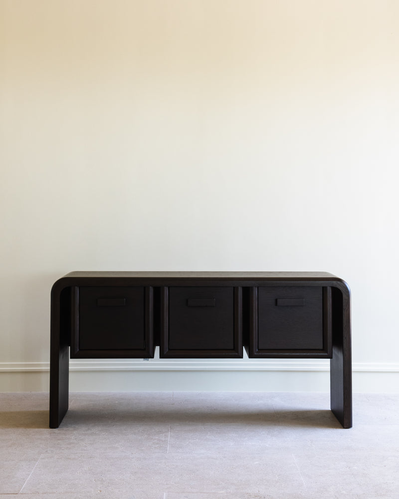 Modern black console table with three drawers and curved waterfall legs