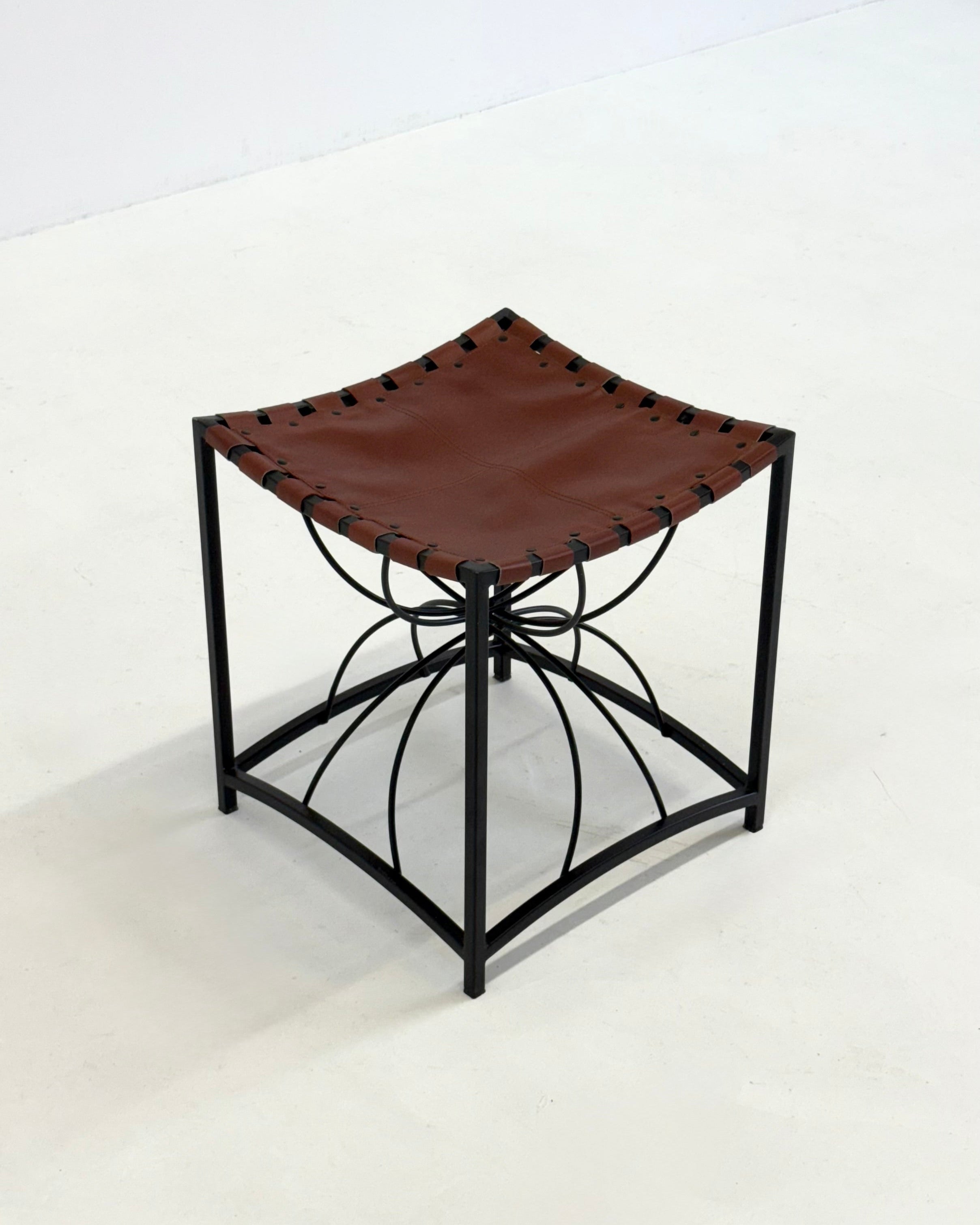 Elegant vintage French stool with black metal and brown leather — in context
