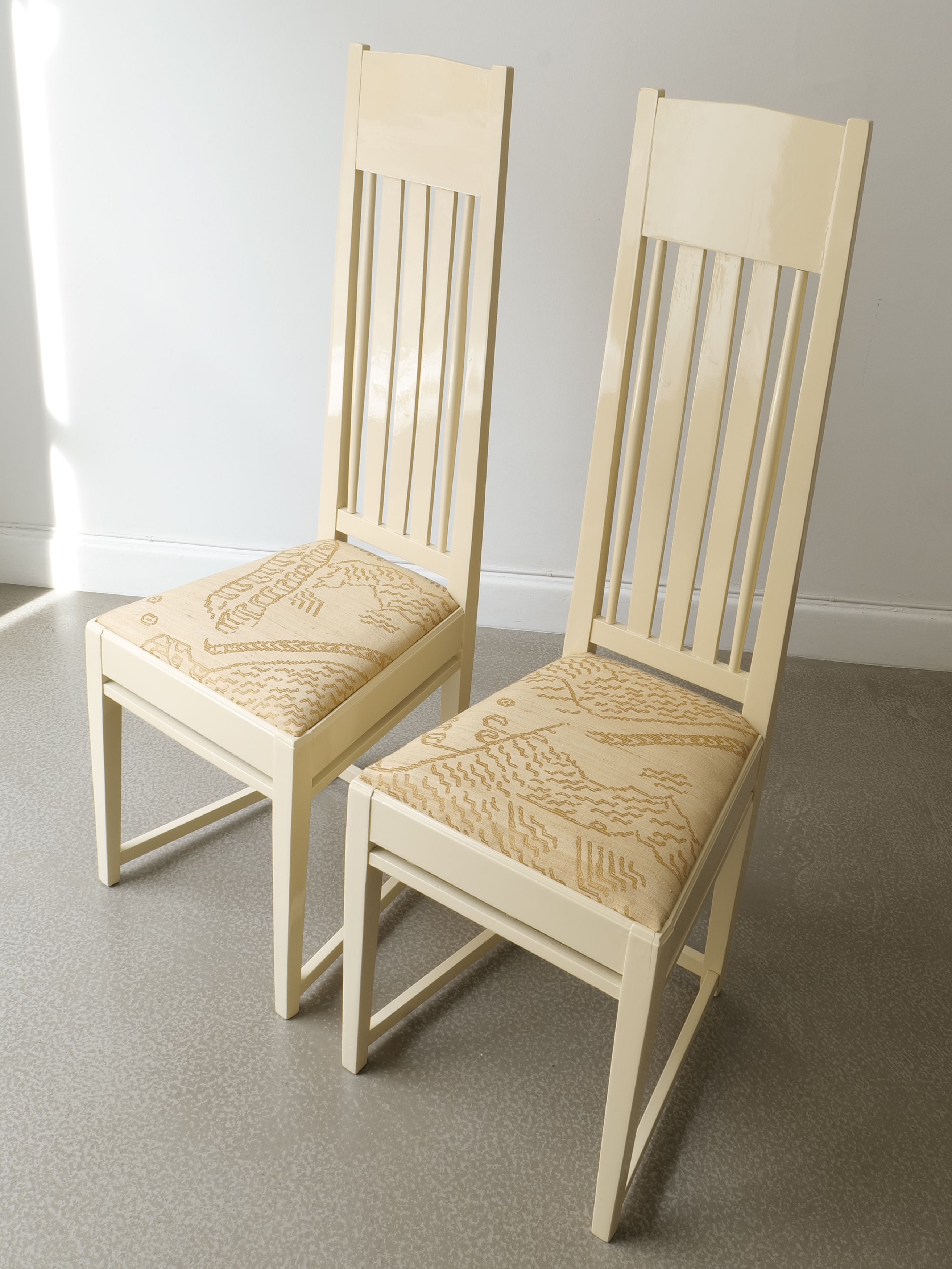 Two cream Swedish Jugend chairs with vertical slat backs and patterned upholstered seats