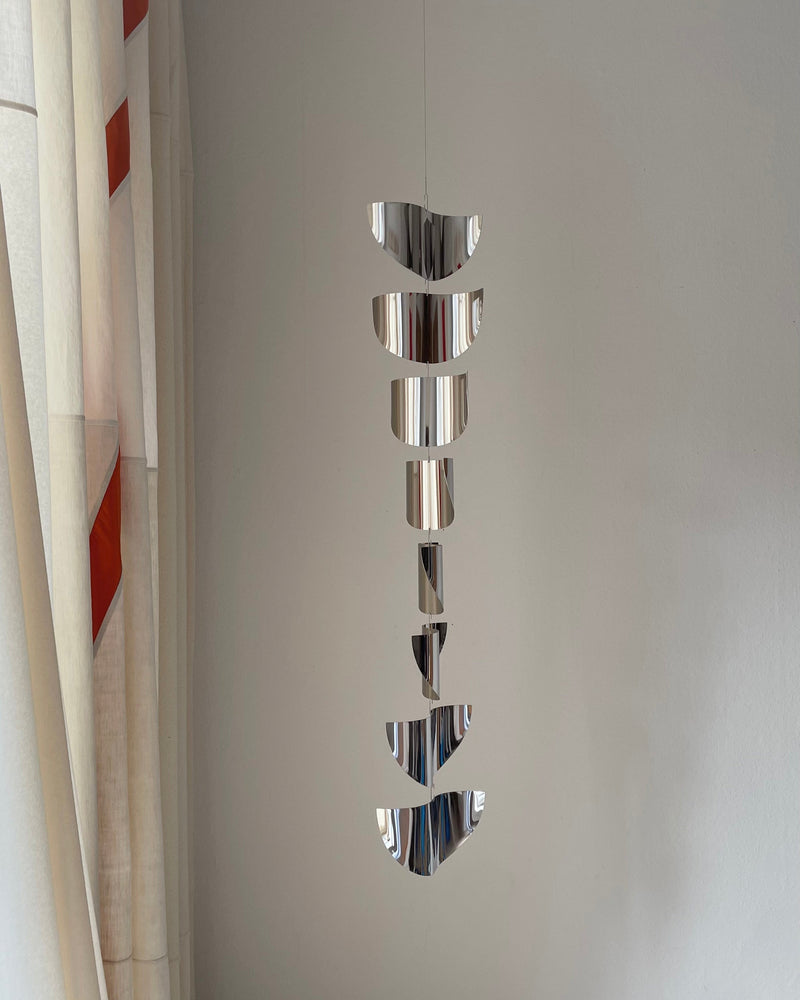 Reflective chrome sculpture with lunar phases hanging vertically