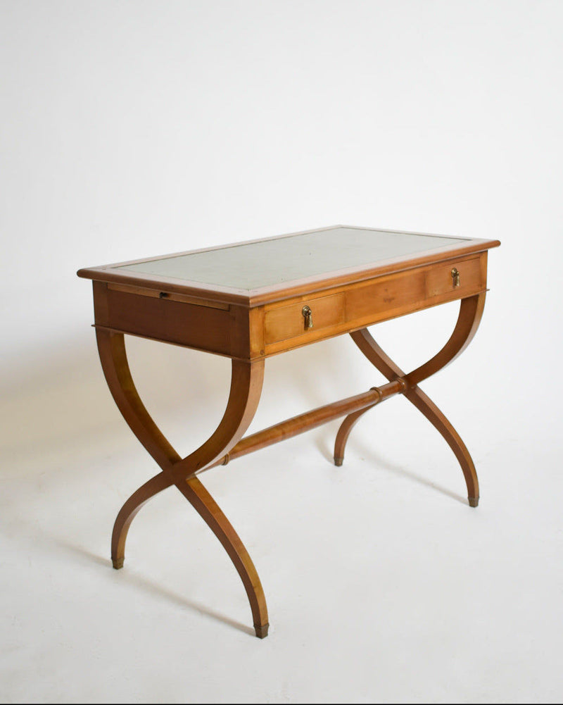A 1970s Directoire style curule console table by Barracuda Interiors, featuring gently curved X-shaped legs, a single front drawer, and a light-colored tabletop, set against a plain white background.