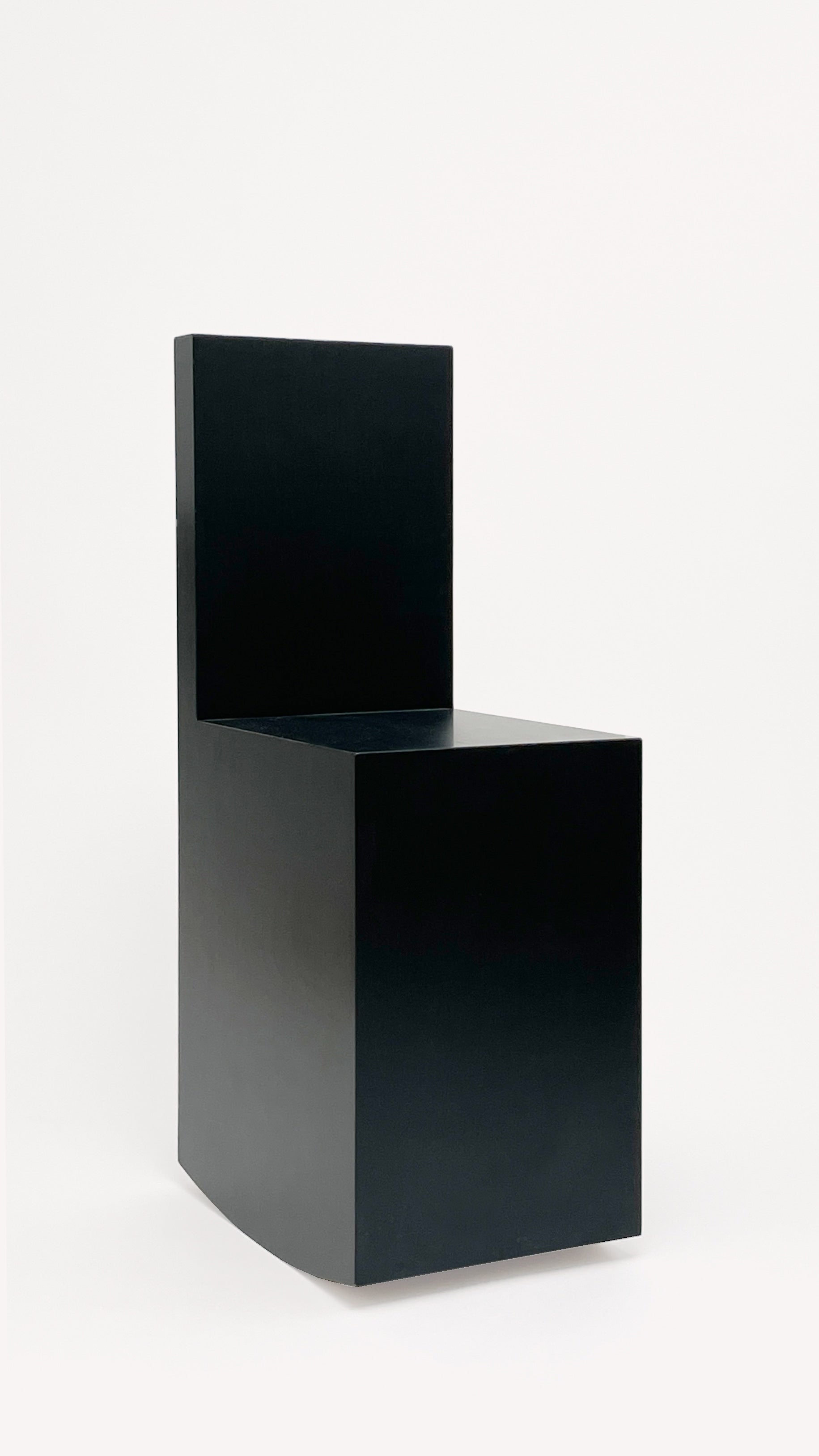 The Art Rocker Chair by GOONS is a minimalist black chair with a cubic geometric design, flat seat, straight backrest, and square edges—an elegant example of contemporary furniture—set against a plain white background.