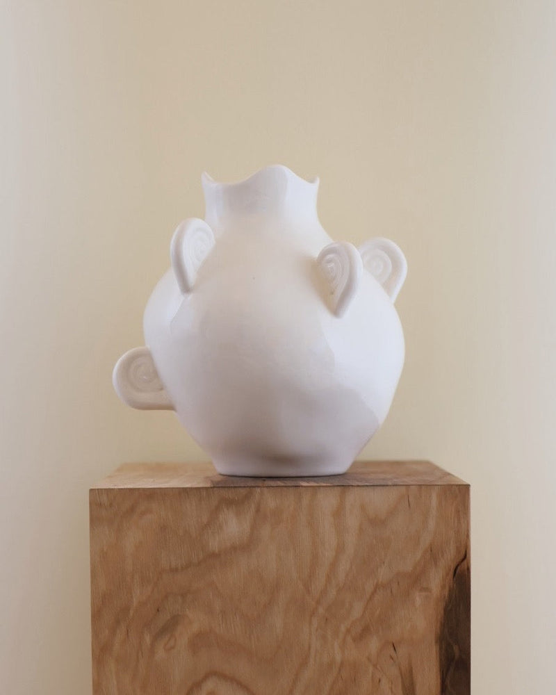 White ceramic vase with horn-like handles and scalloped rim detail