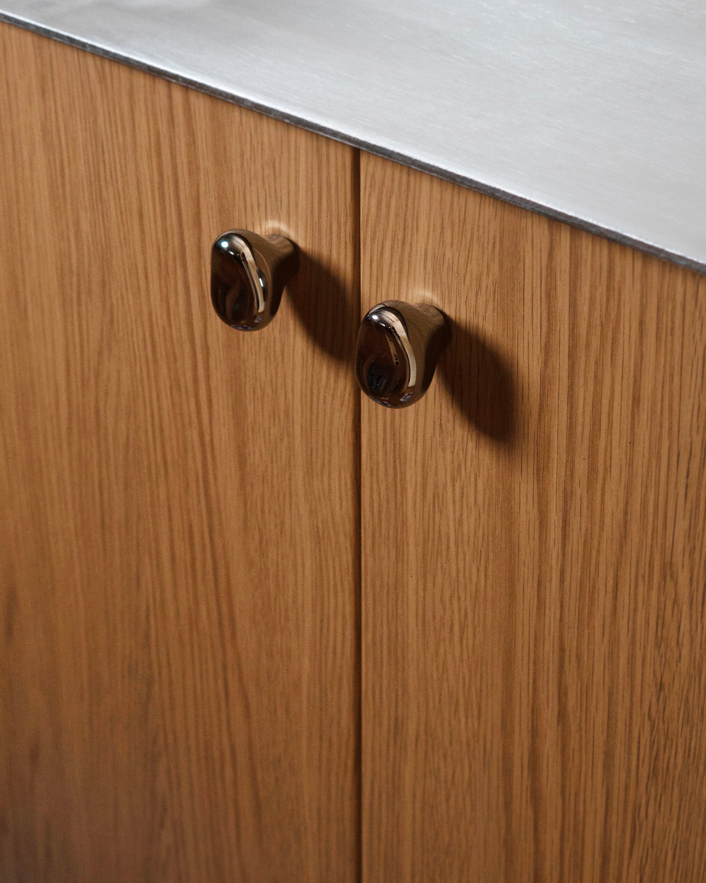 Rud Knob - Titanium — back view on wooden cabinet doors