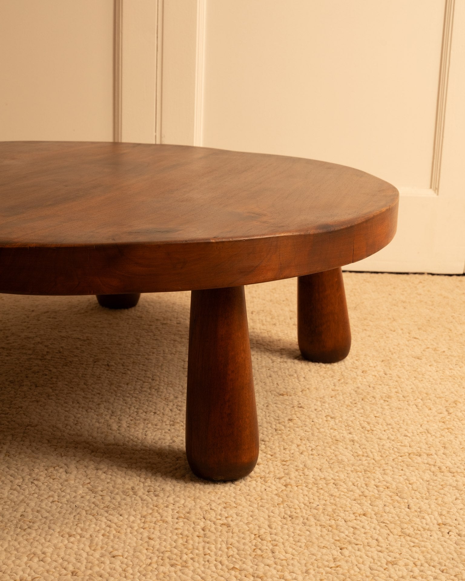 Rounded wood coffee table with cylindrical legs detail view