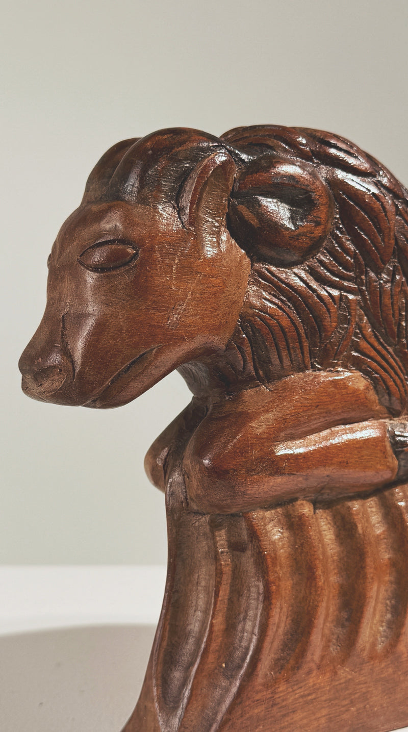 Profile view of carved wooden ram sculpture with detailed mane