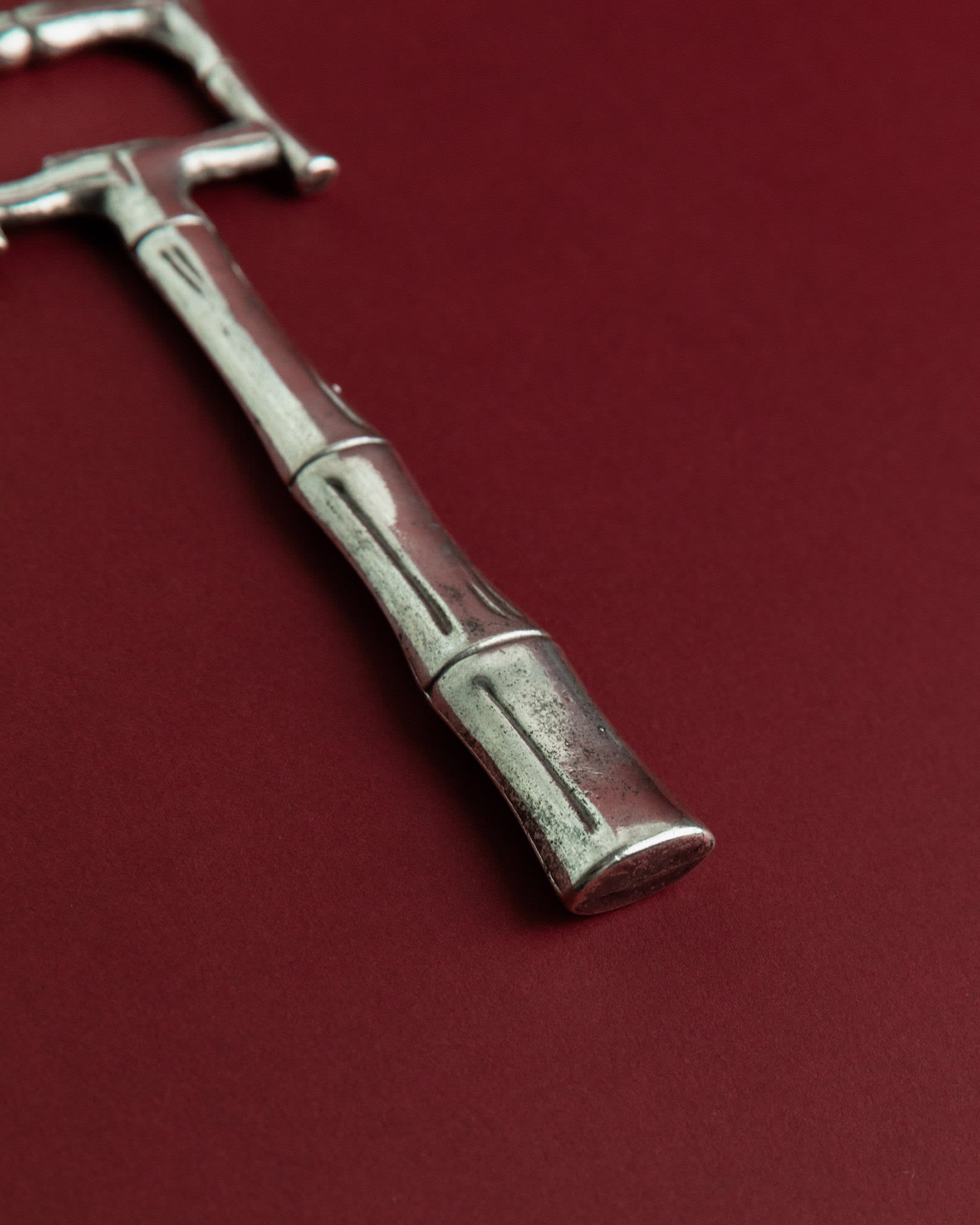 Vintage 1970s Silver Plated Bottle Opener, Bamboo Design — angled view on burgundy background