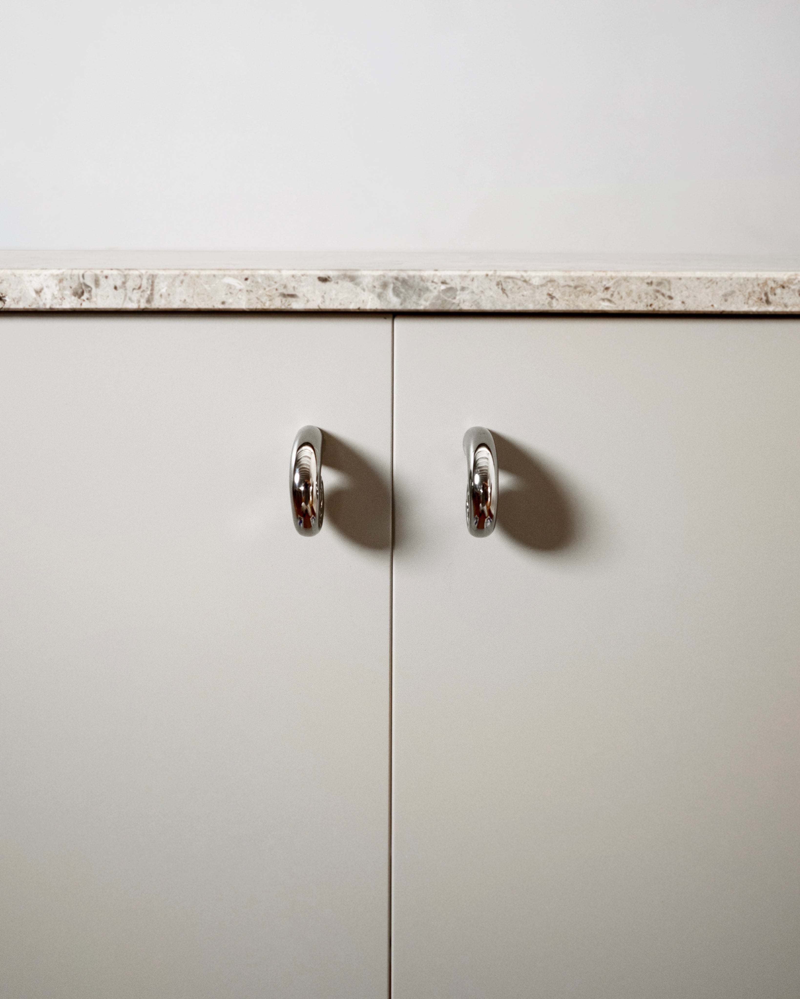 Noelle Knob - Titanium — front view on minimalist cabinet doors