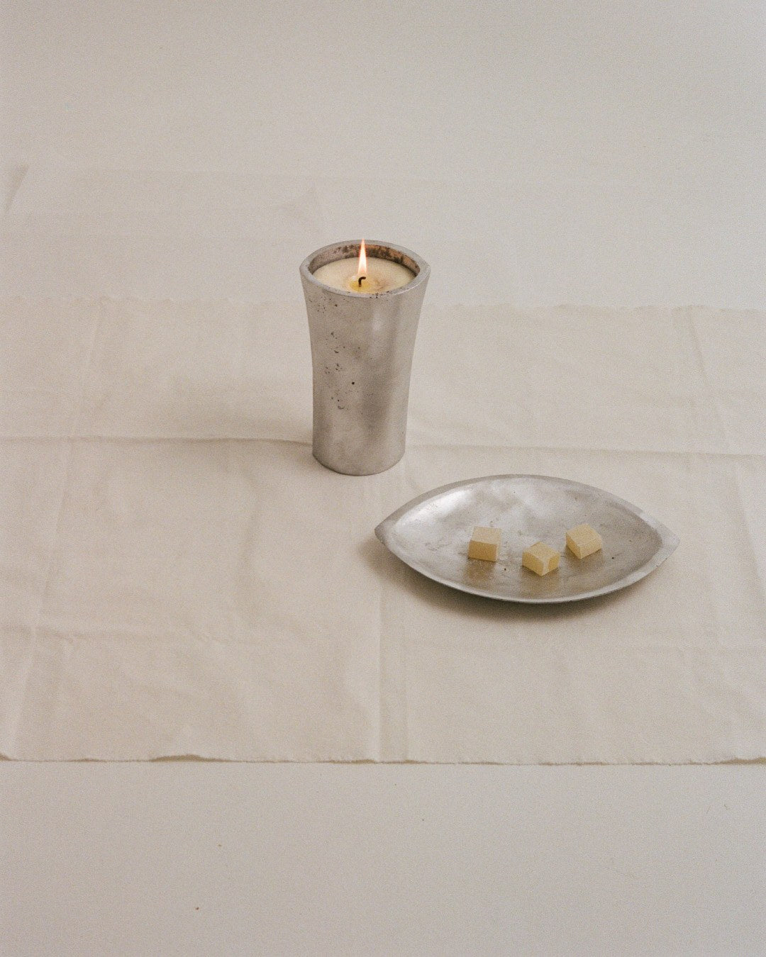 Aluminium Candle Sculpture — close-up of candle on white fabric