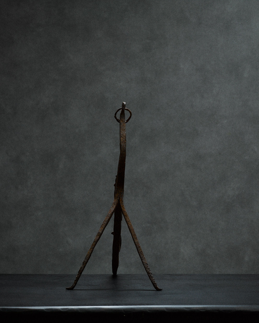 handcrafted iron sculpture with primal animal motifs — side angle against gray backdrop