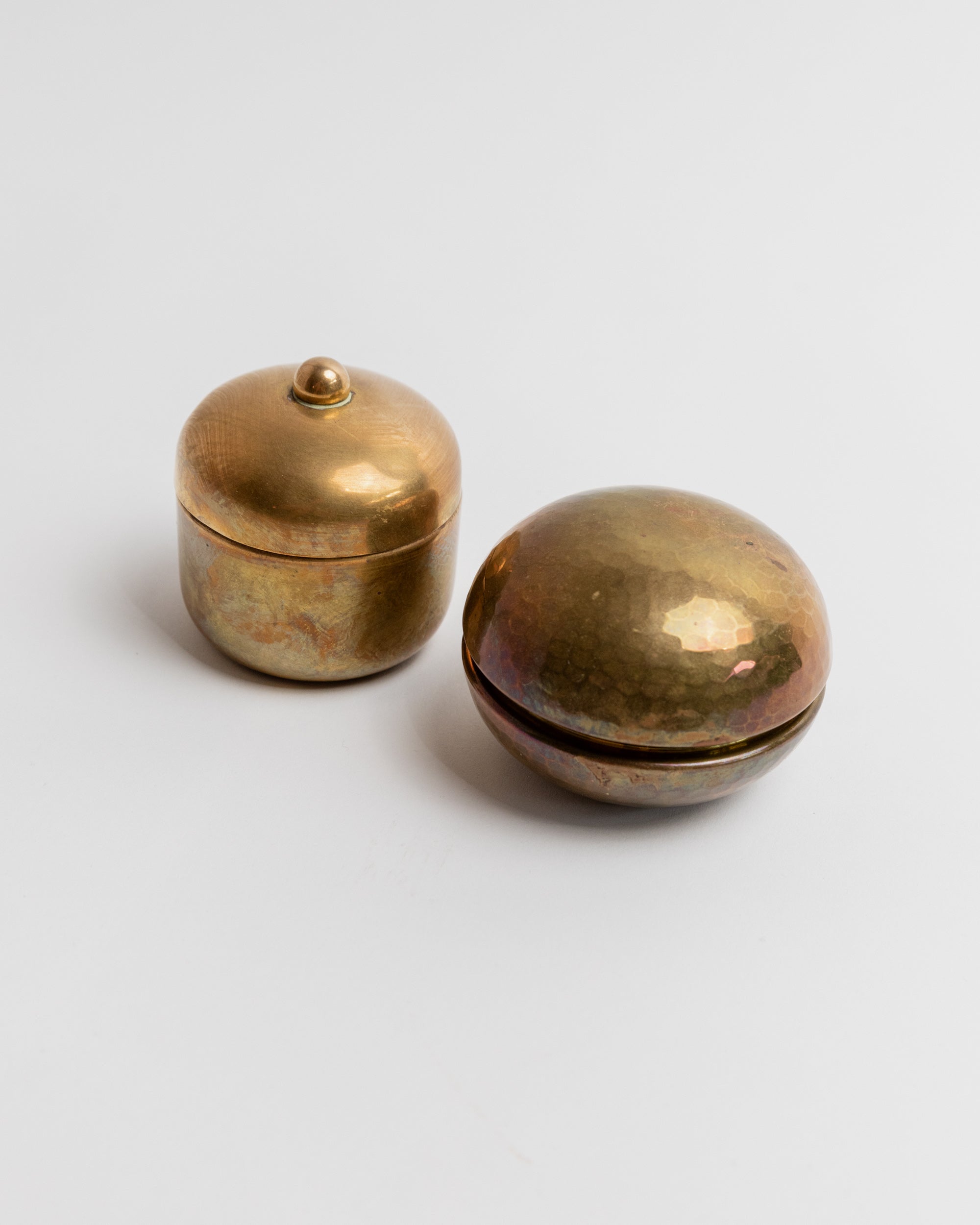 Two vintage brass tins with weathered patina, one lidded cylindrical container and one oval bowl-shaped piece
