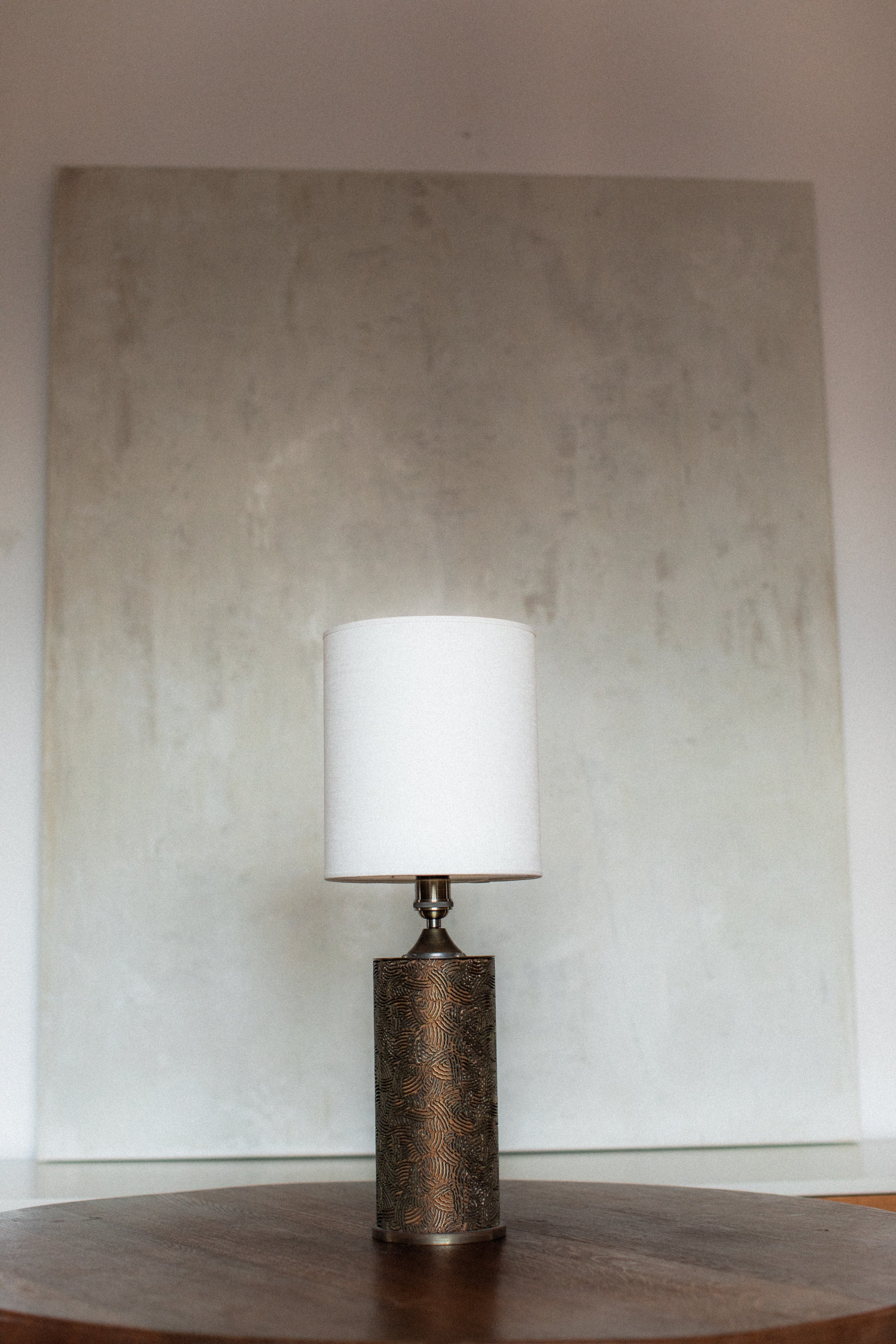 Monolithic table lamp with patterned bronze base and white shade