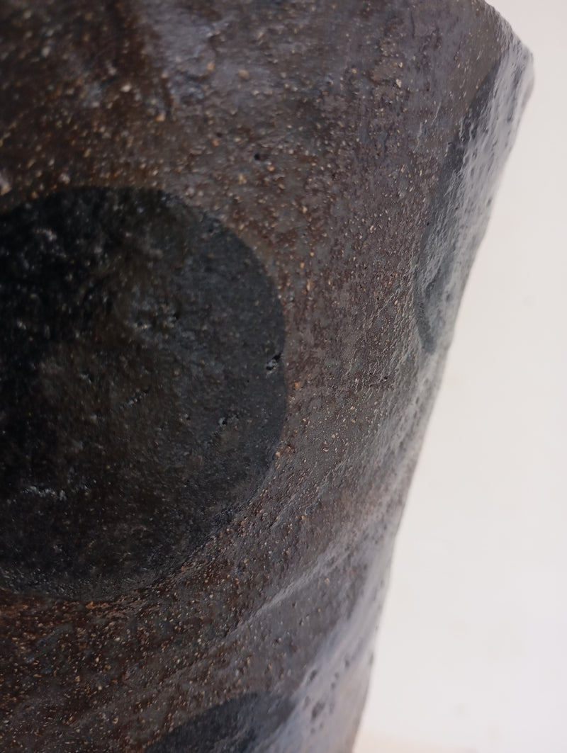 Close-up of the Claire Pain Stoneware Vase, featuring a textured dark brown finish with black circular patterns, shown against a plain white background.
