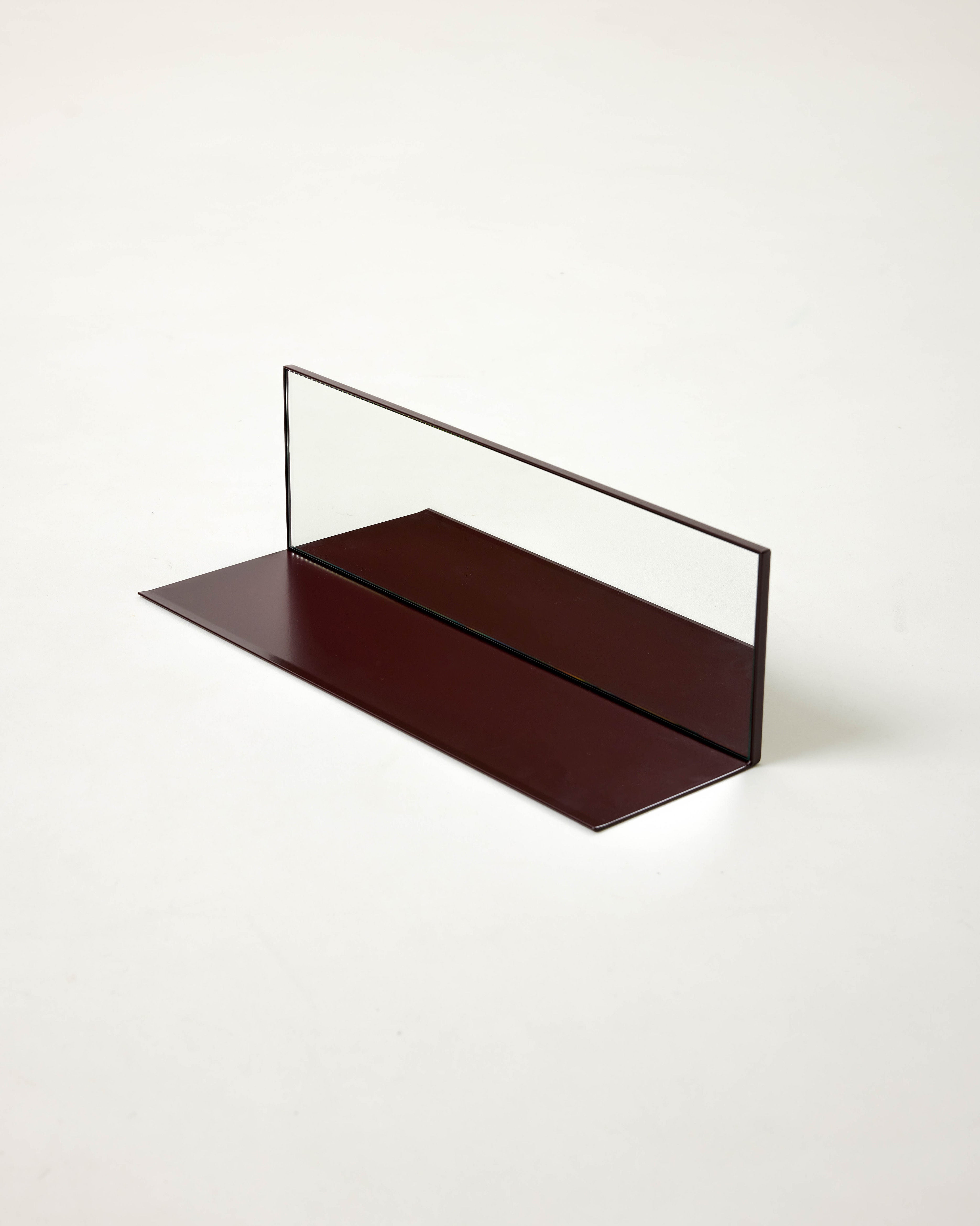 The Mirror Steel Shelf by Dot Objects features a maroon rectangular base with a vertical clear glass panel, showcasing minimalist customisable shelving against a plain white background.
