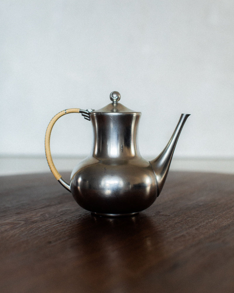 Polished pewter Art Deco teapot with rattan-wrapped handle