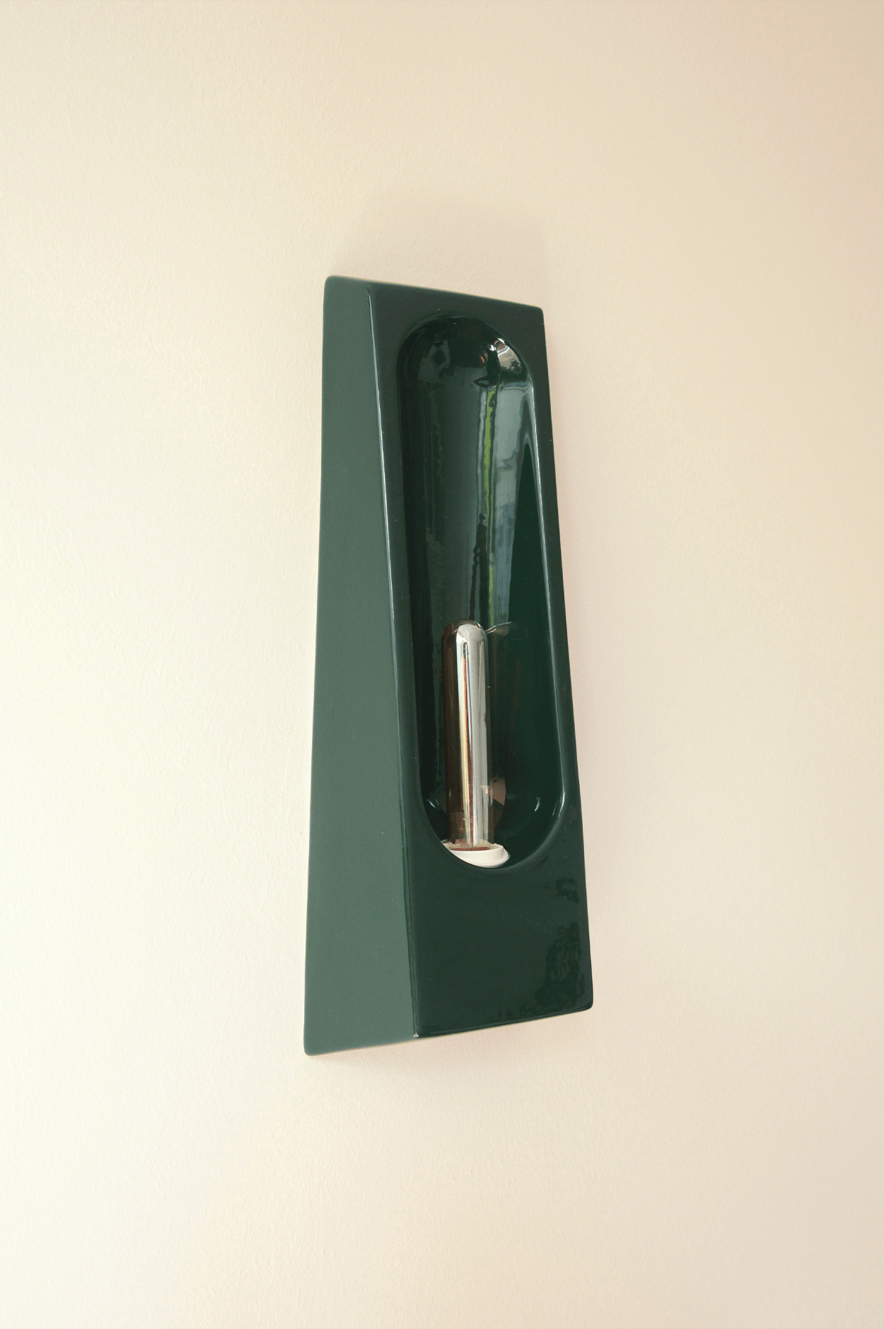 The Alcove Verde wall sconce by Violaine d'Harcourt features a modern dark green ceramic design with sleek lines and a cylindrical metallic bulb, perfect for adding stylish indoor lighting to any space.