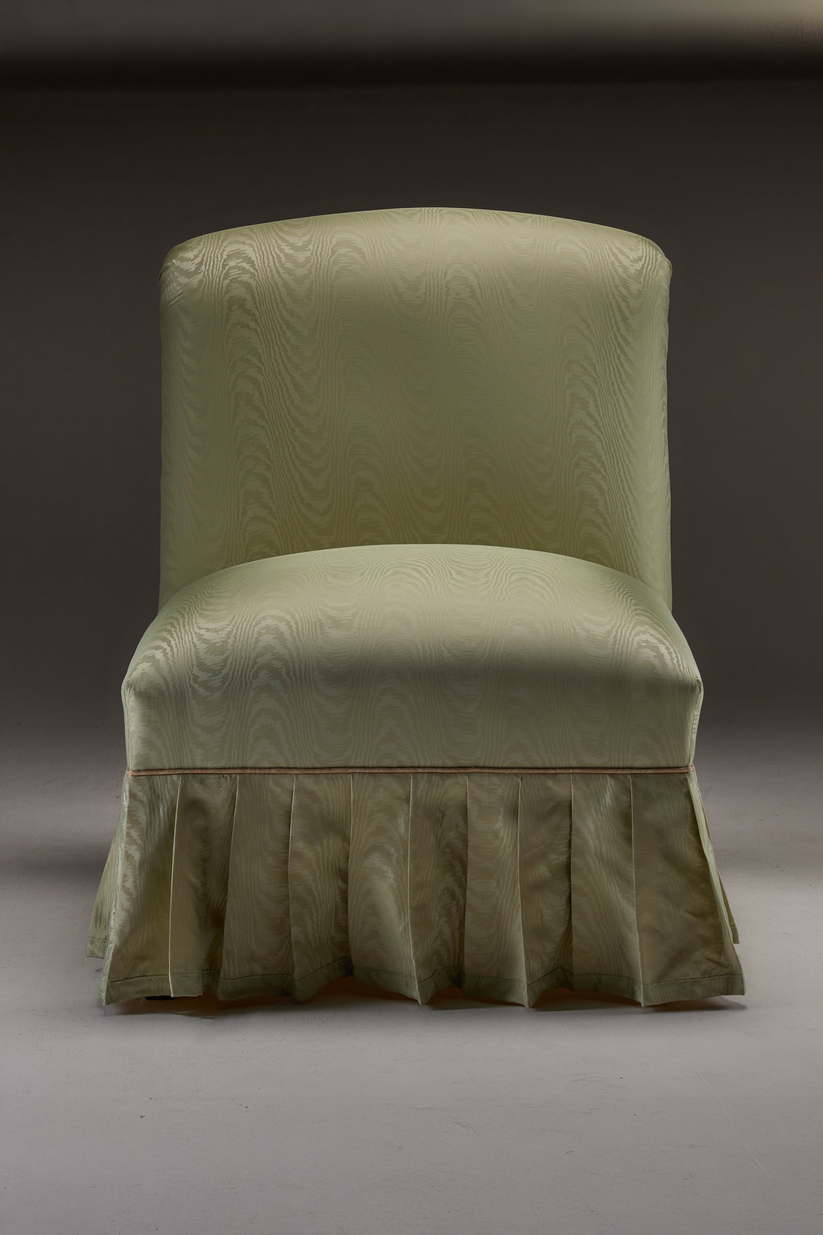 HESTIA SLIPPER CHAIR — front view of upholstered green fabric with pleated skirt