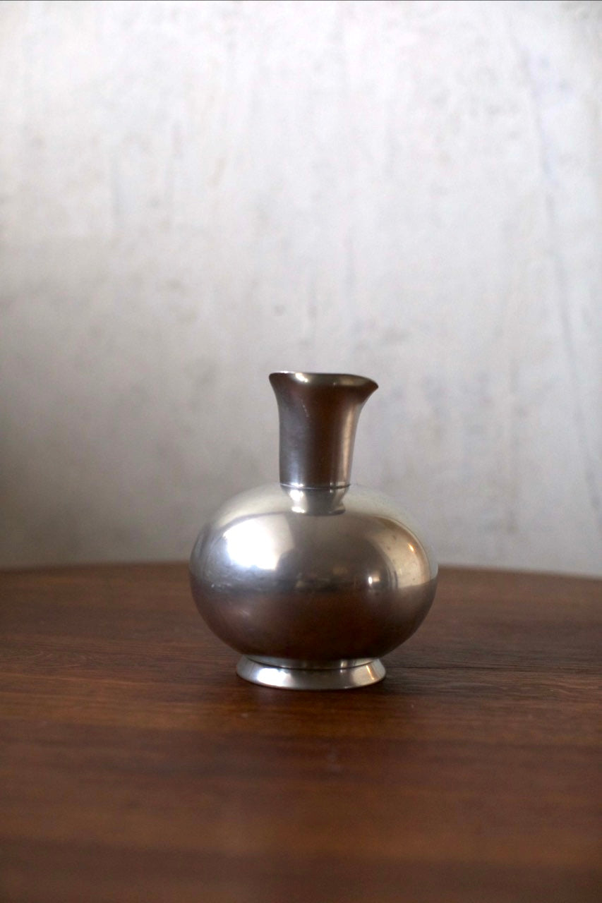 Tin Vase — top view of polished silver surface on wooden table