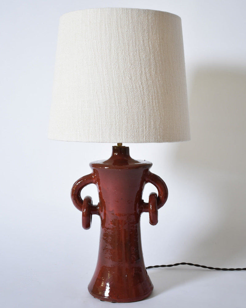 The "Kasaï" Red Handles Ceramic Table Lamp by Barracuda Interiors features a glossy red base with twin decorative handles and a textured cream shade. Made in Portugal, it's showcased against a plain white background.