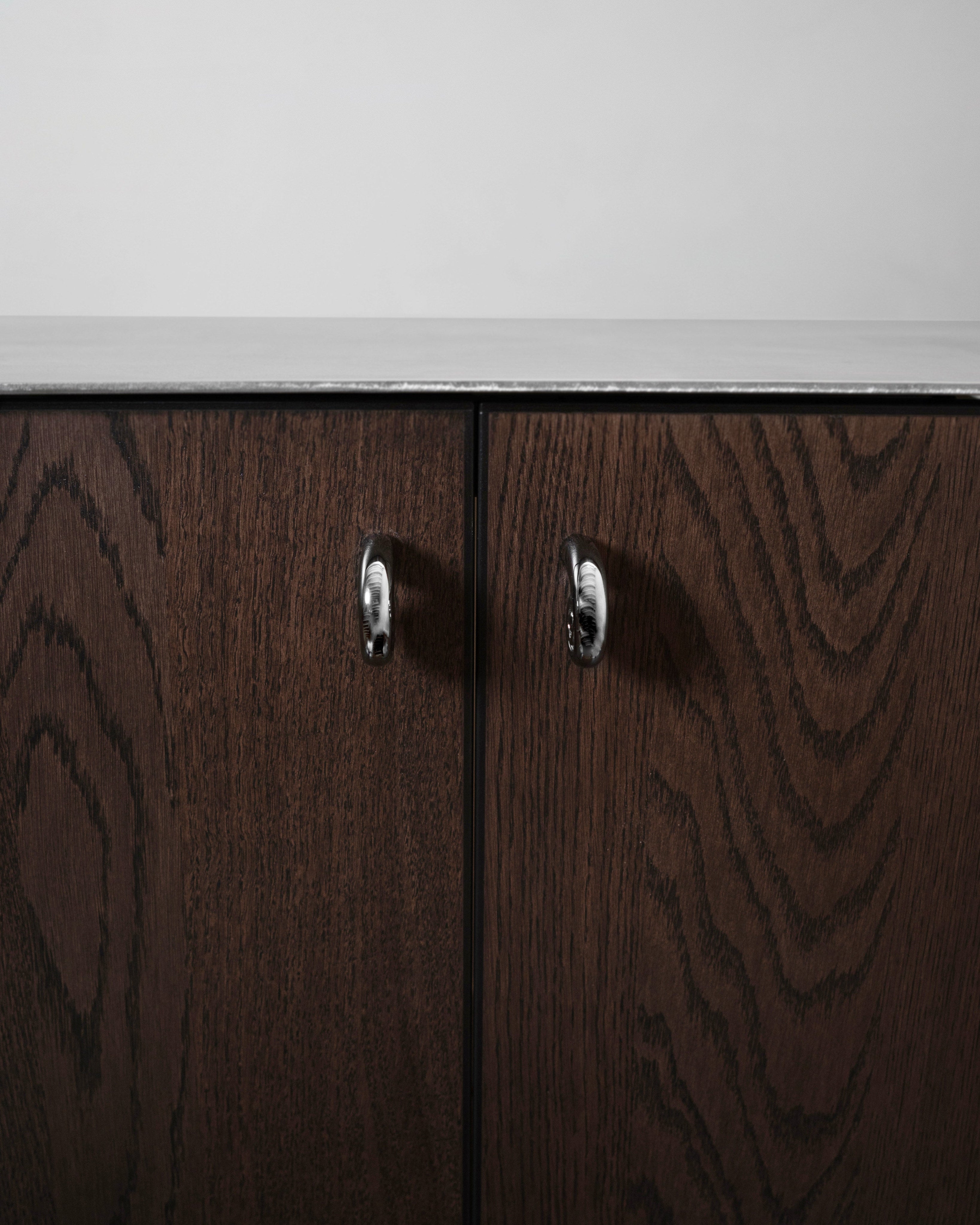 Noelle Knob - Titanium — front view on dark wooden cabinet