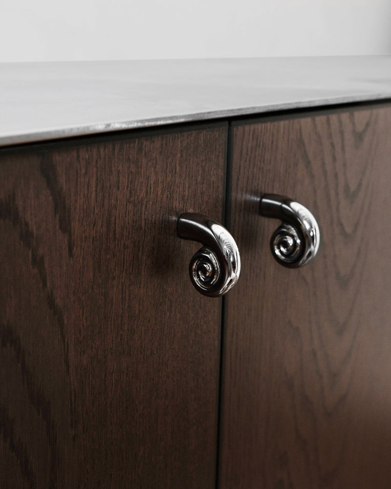 Noelle Knob - Titanium — close-up of knob on dark wood cabinet