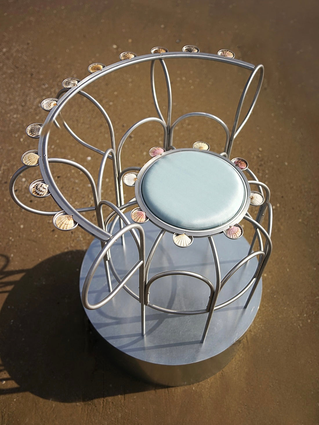 The Armchair With Shells — side angle showing metal frame and shell accents