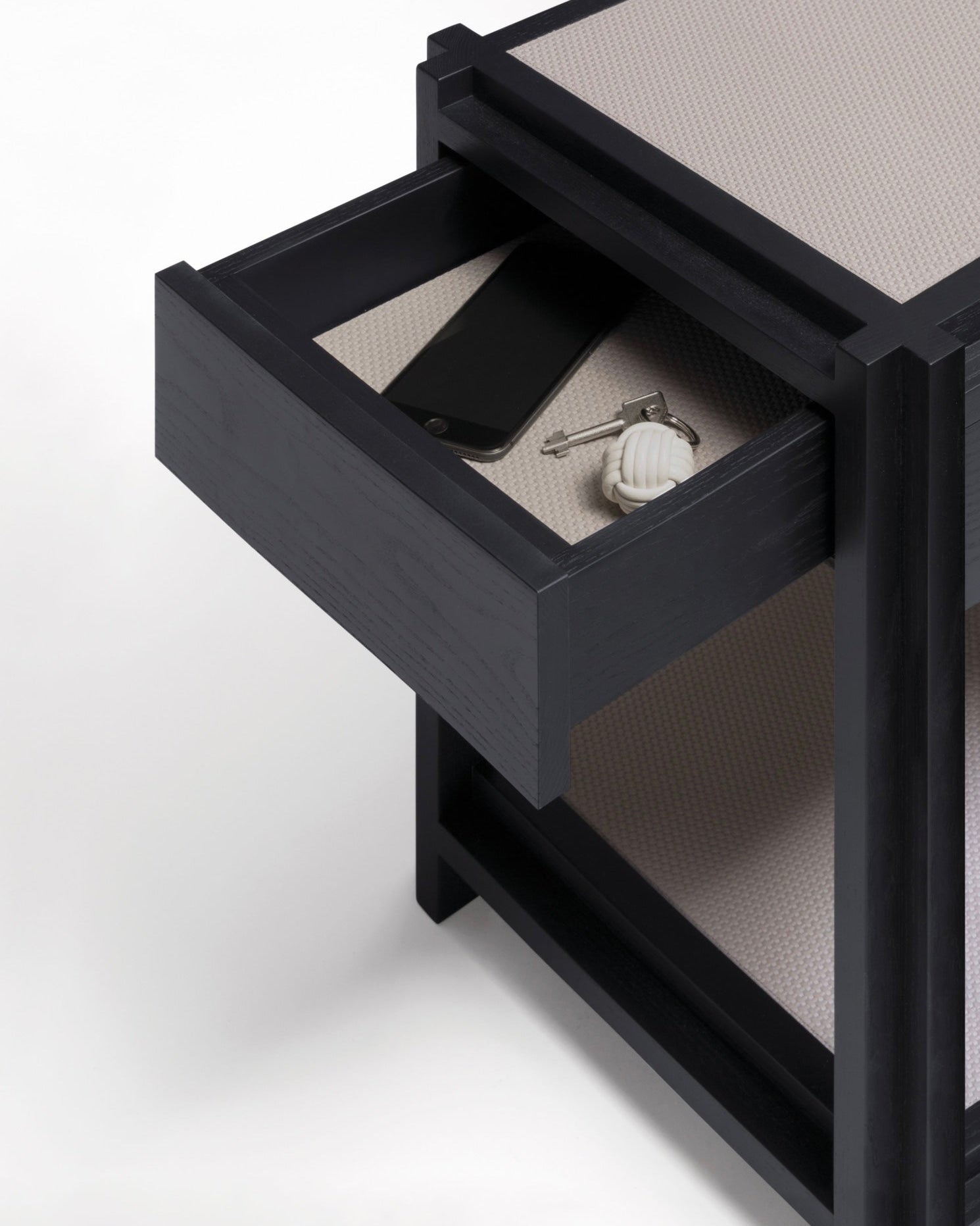 Square bedside table with open drawer showing leather accessories
