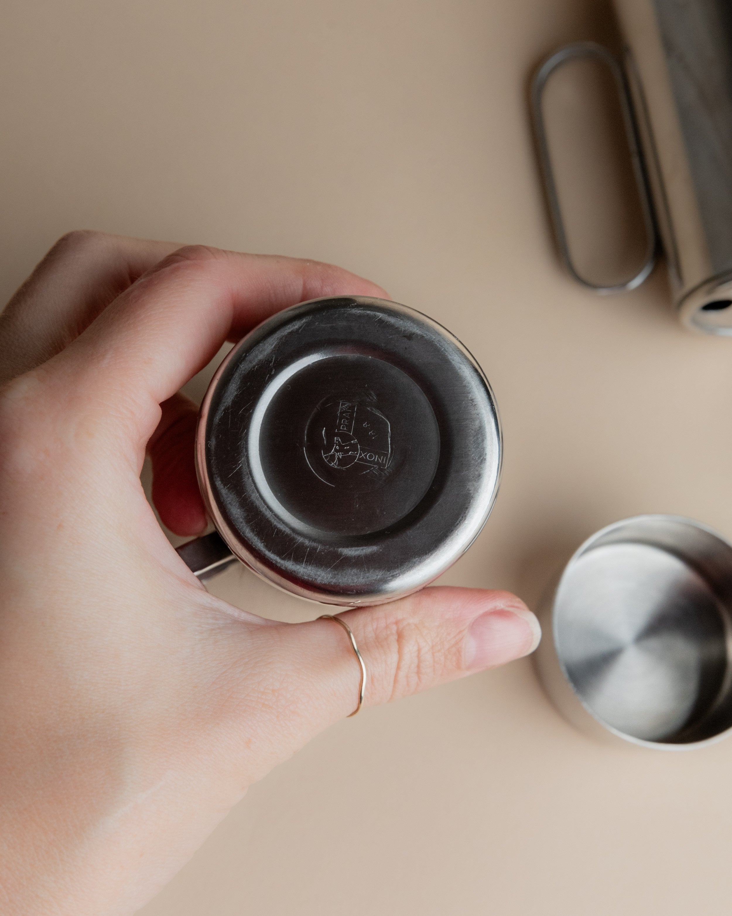 Hand holding stainless steel oil vinegar cruet showing base detail