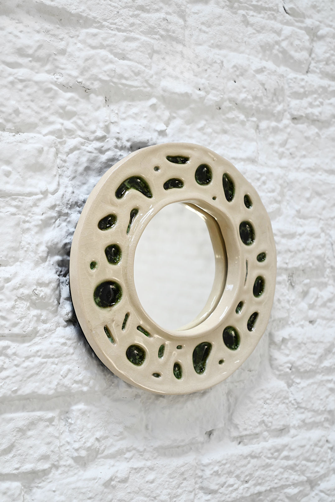Organic ceramic mirror frame detail showing cream glaze with moss green accents