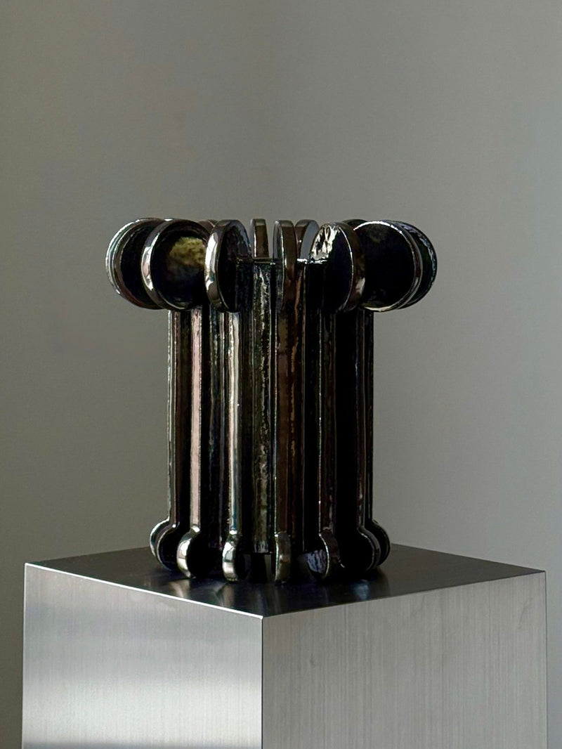Black glass cylindrical vase with curved handles by Devin Wilde