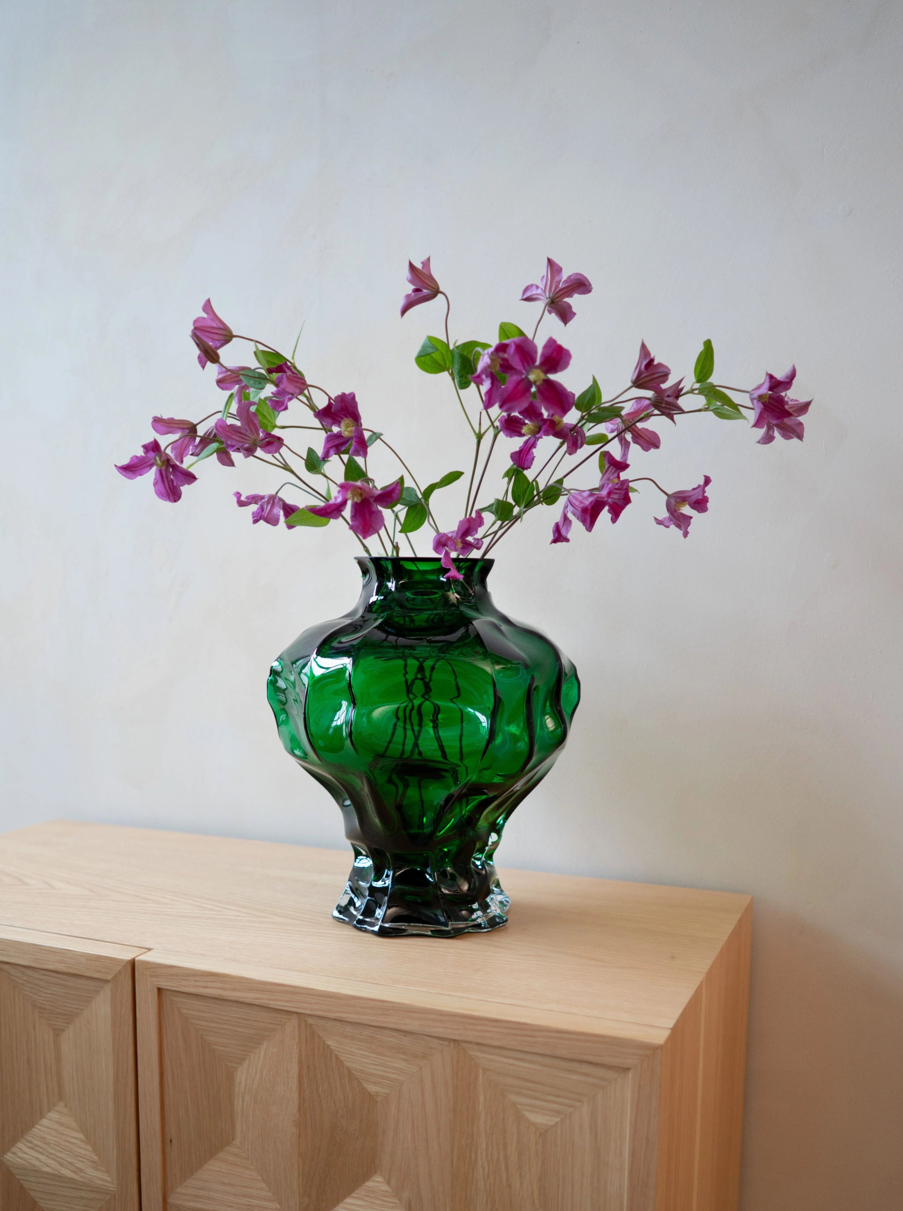 Ammonit Vase - Green — close-up of green glass with flowers