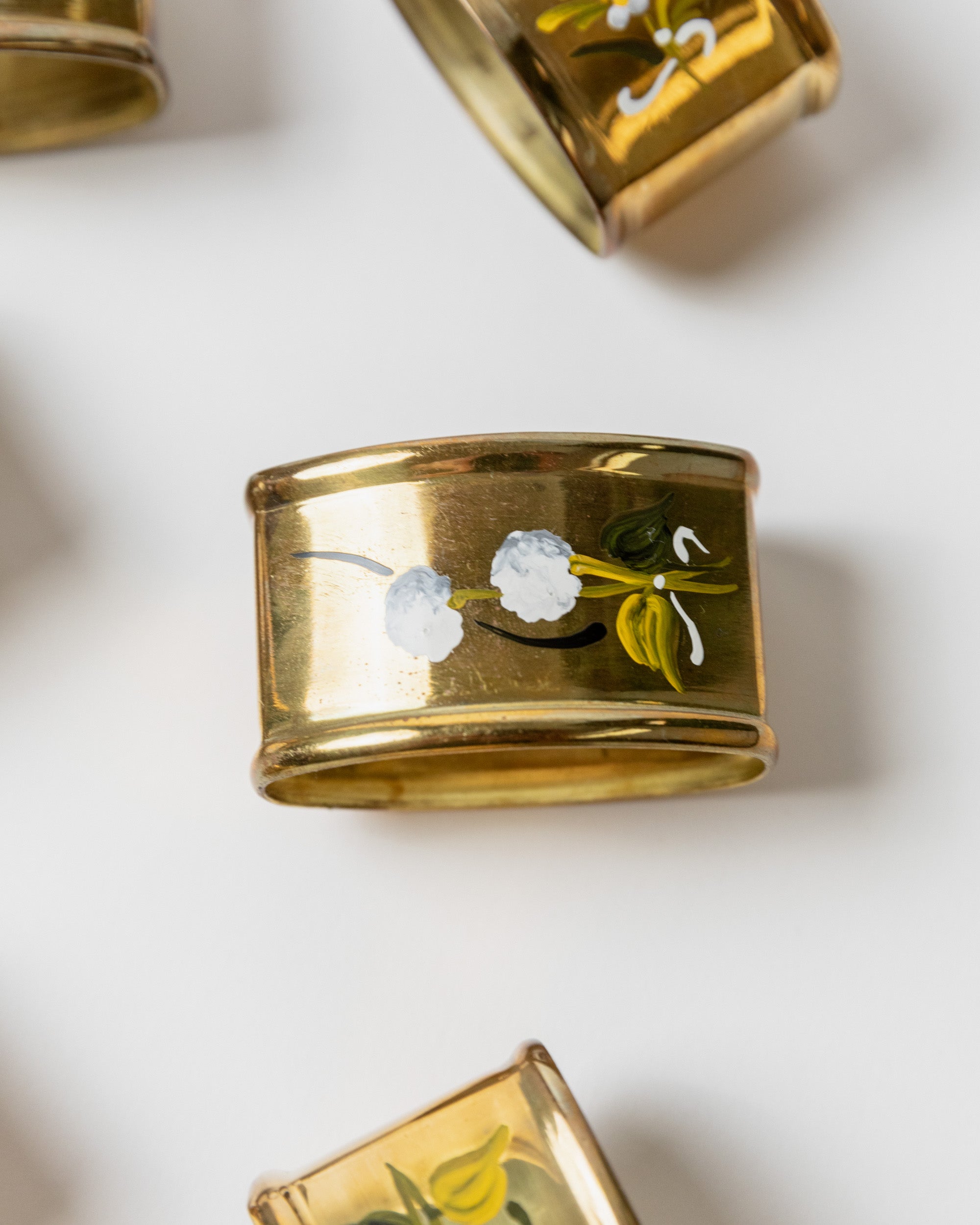 Close-up detail of brass napkin ring with white floral motif