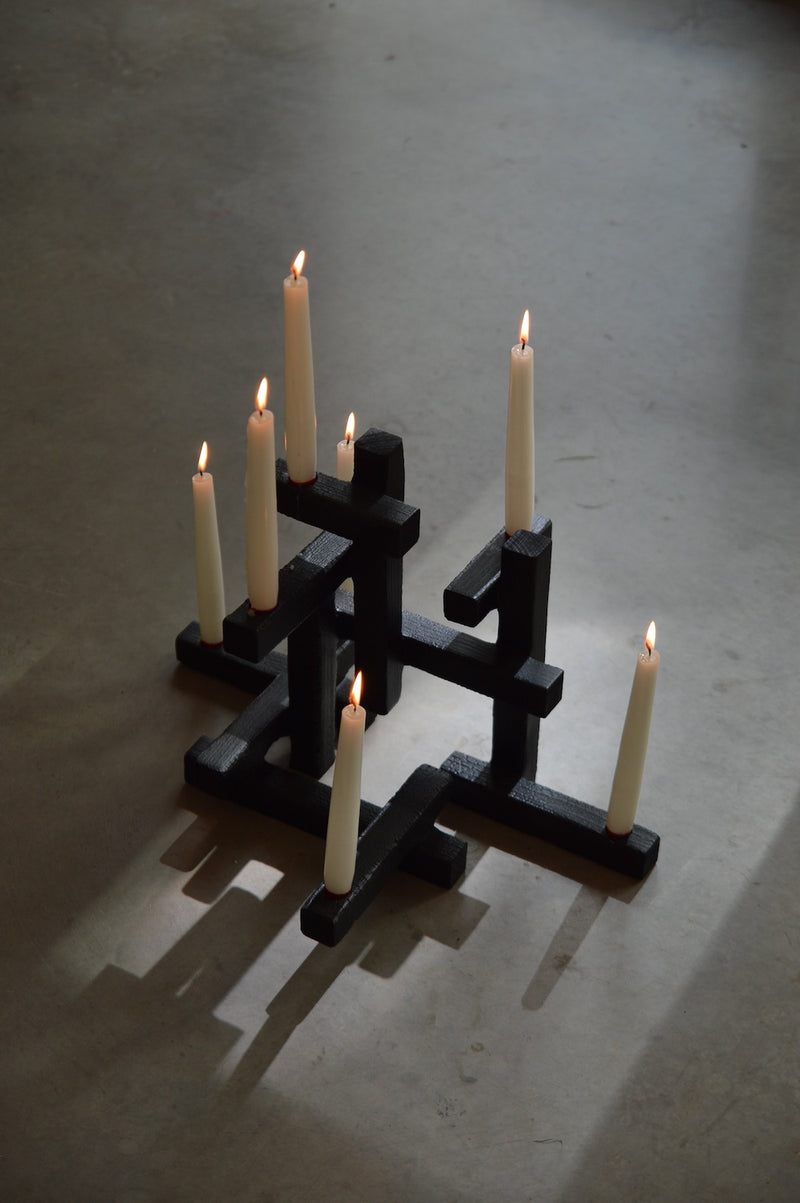 Black geometric candleholder with seven lit candles in Tetris design