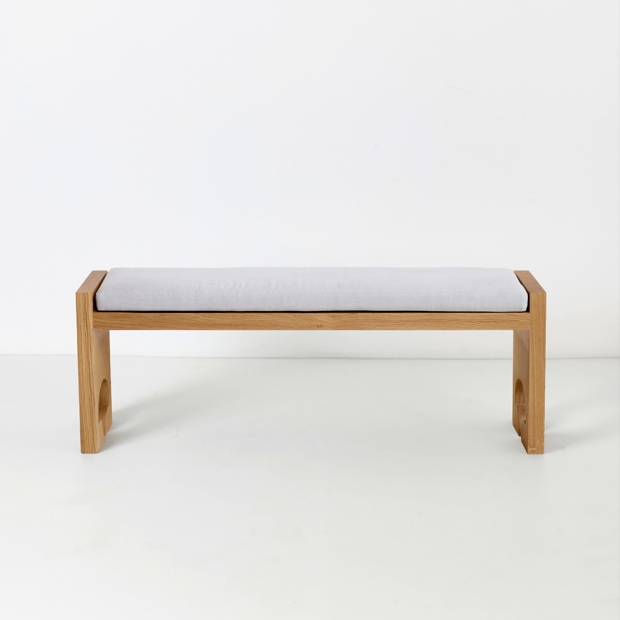 Quinta Bench — front view of oak frame with gray cushion