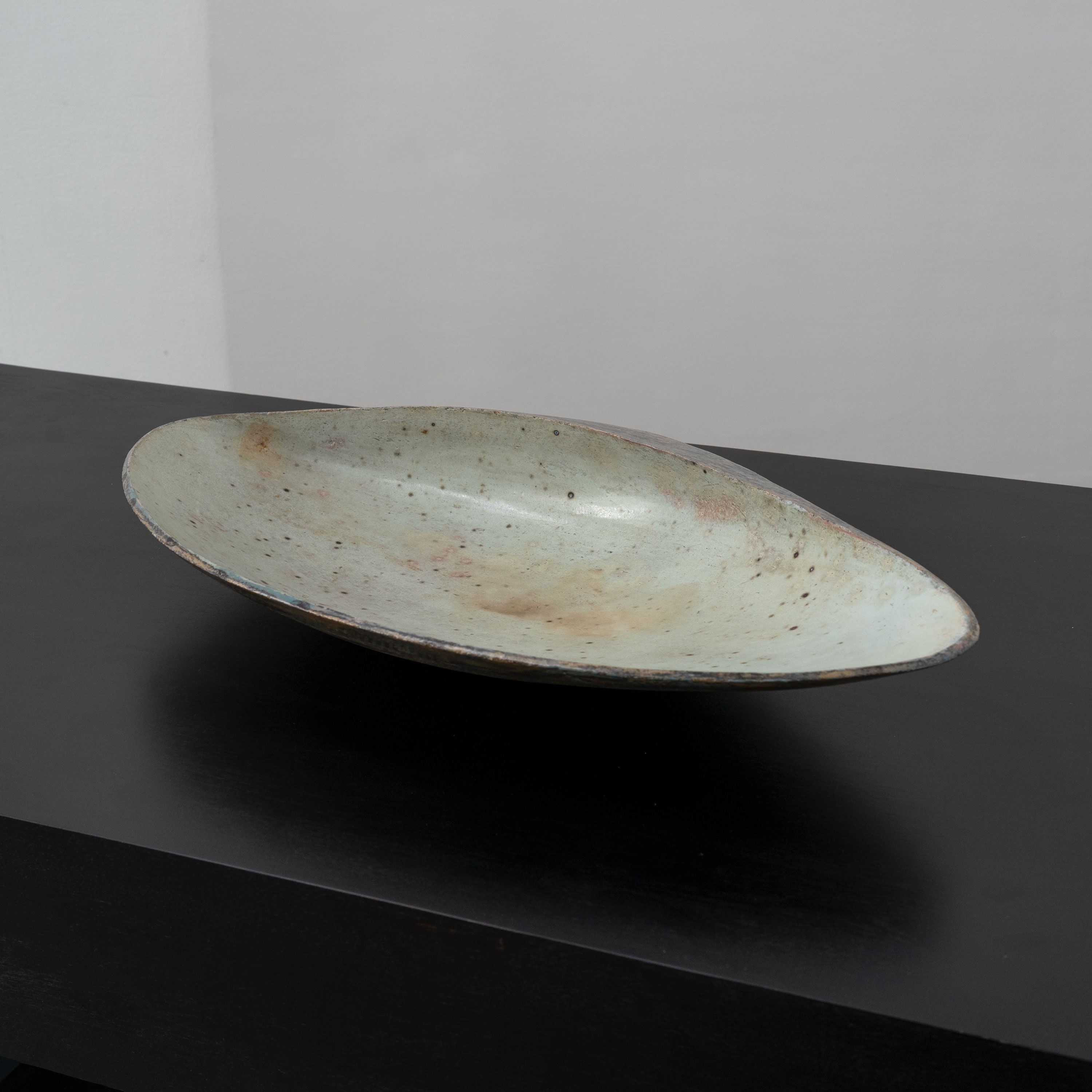 Large speckled ceramic bowl in profile view on dark surface