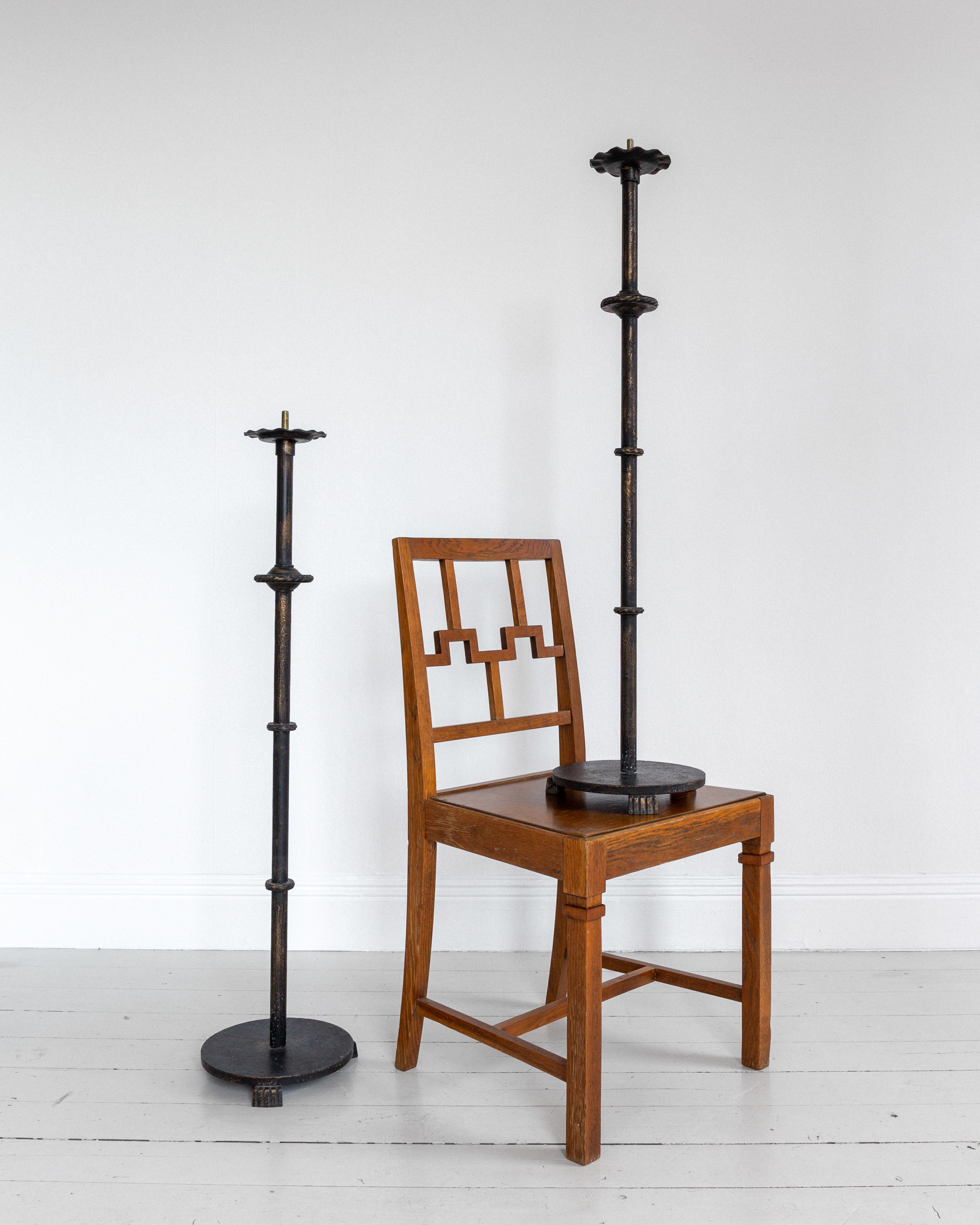 Pair of Monumental Cast Iron Floor Candleholders by Böhlmarks, Sweden, 1930s — positioned beside wooden chair in minimalist s