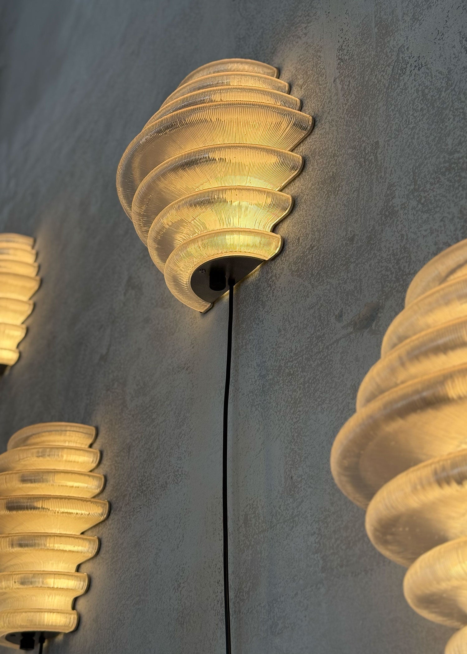 Stacked ribbed glass shades of illuminated Hive wall light