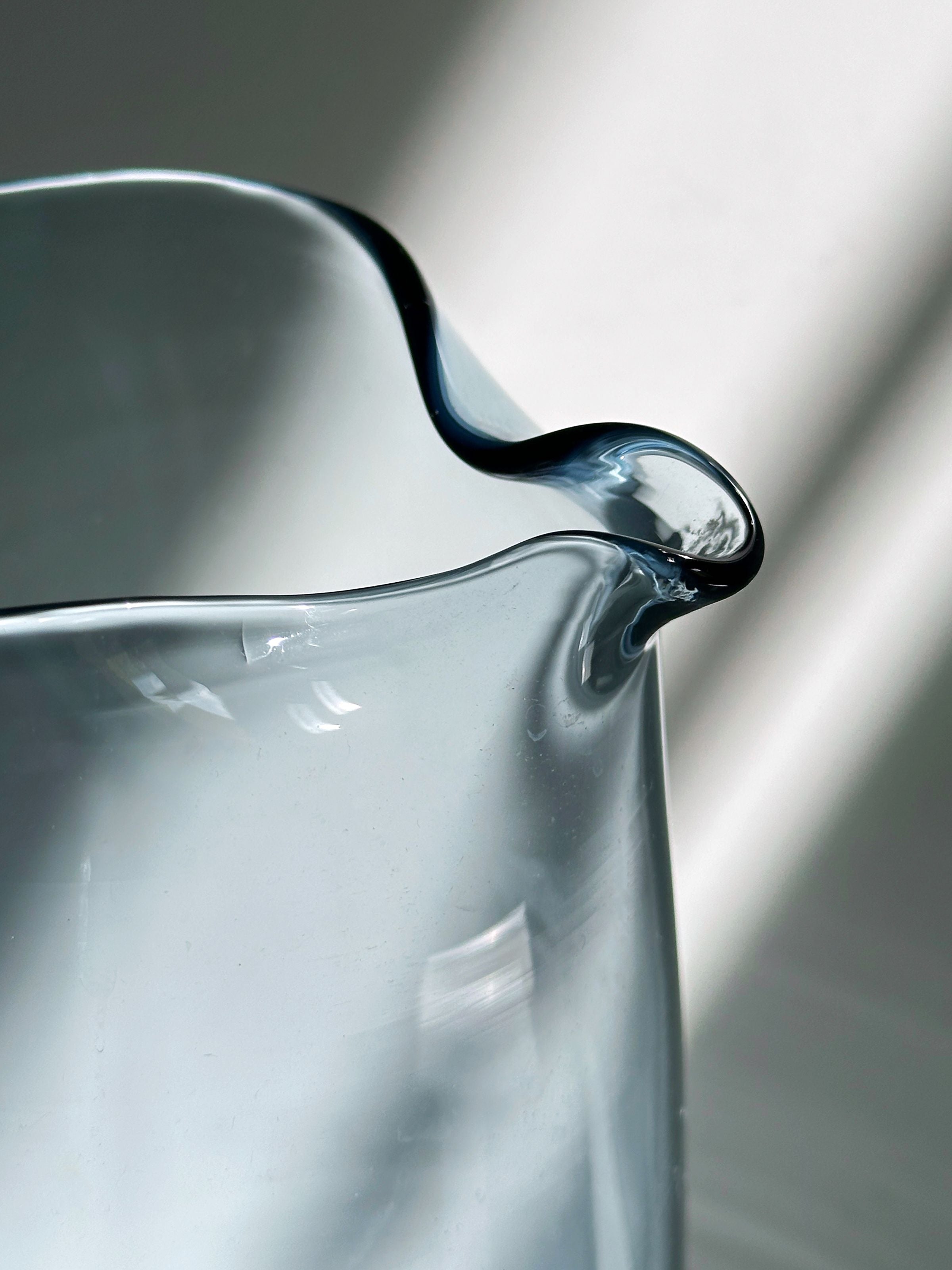 Blue glass carafe spout detail showing curved rim and transparency