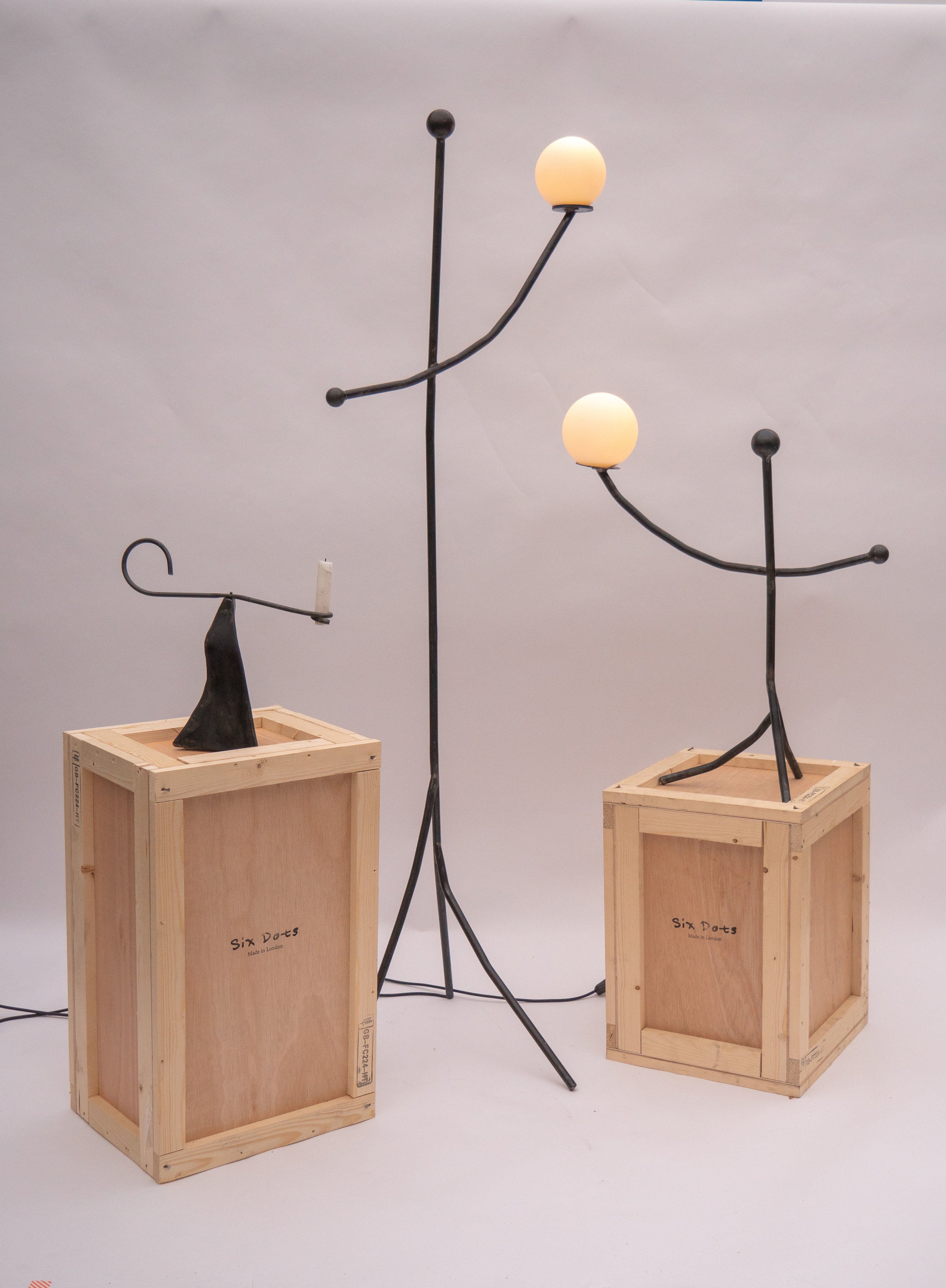 Black sculptural candle holder with glowing orbs on wooden crates