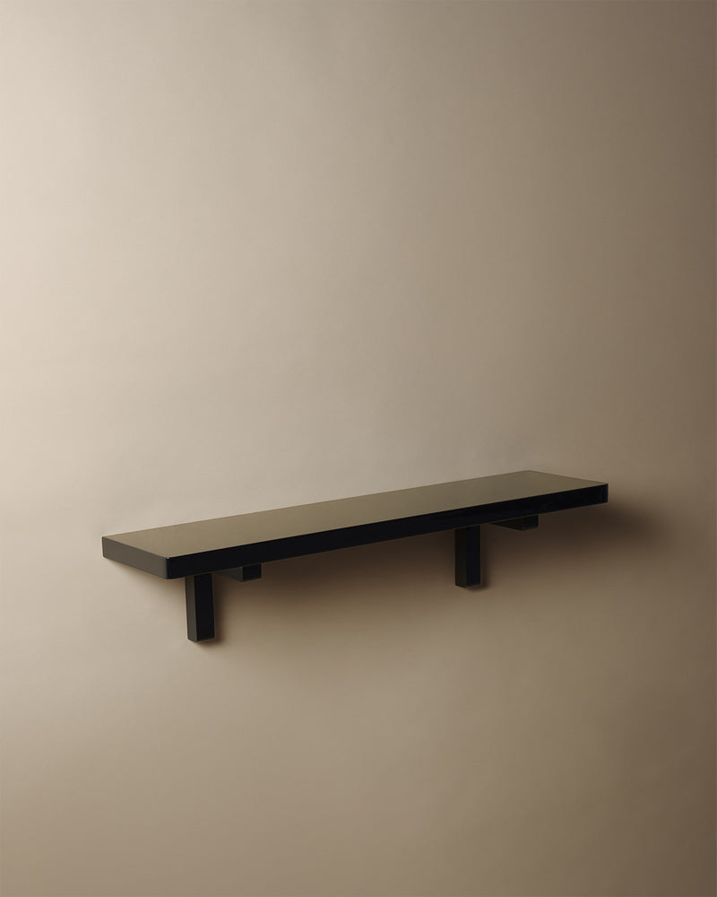 Minimalist black lacquered wall shelf with cylindrical legs