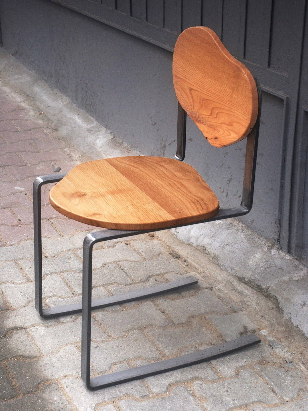 Carmen Chair' in Chestnut Wood by ZAROLAT Studio — angled view on outdoor patio