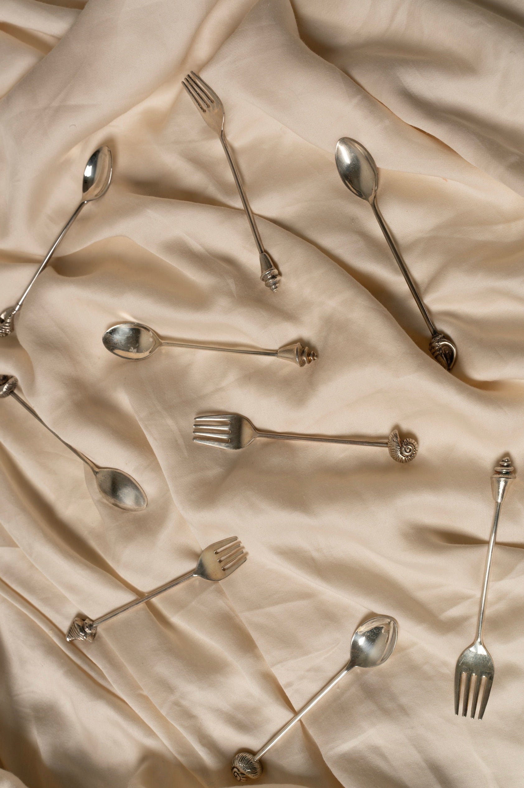 Silver Shell Spoon Set of Two — arranged on soft beige fabric