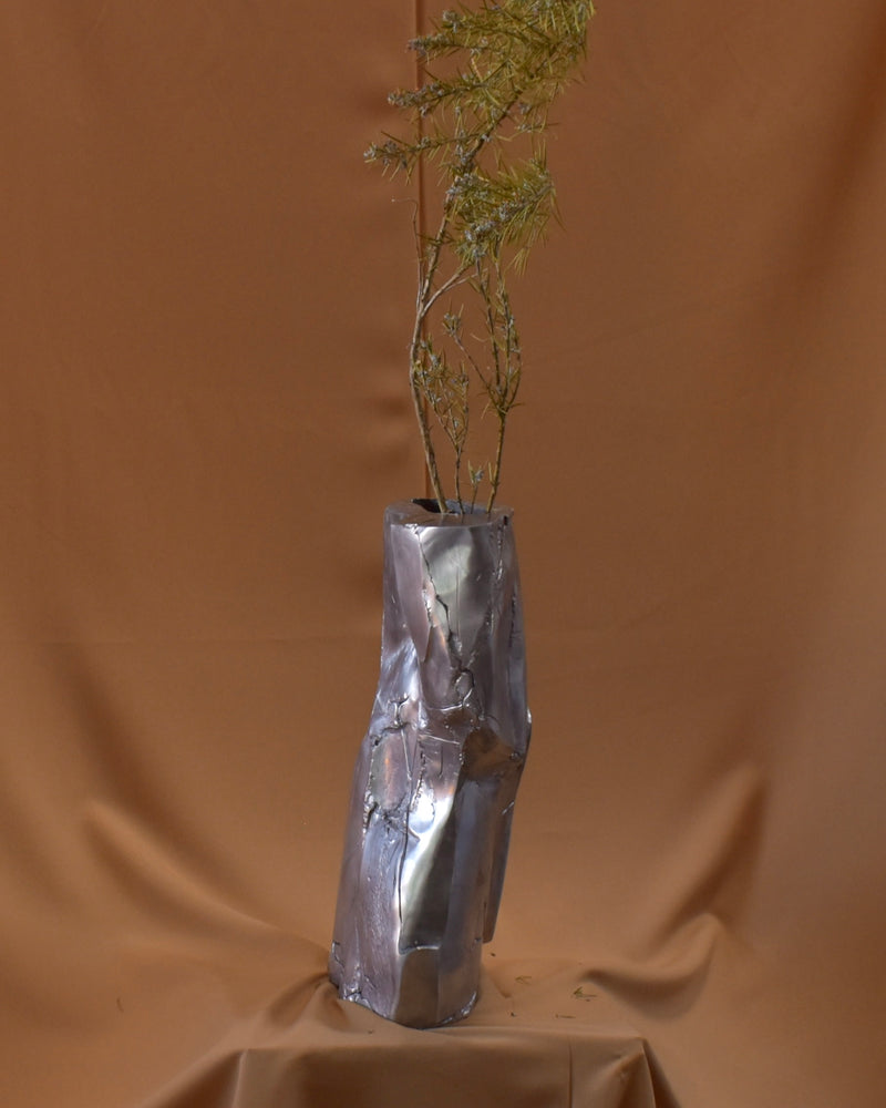 Cast aluminum vase with patchwork texture holding dried botanicals