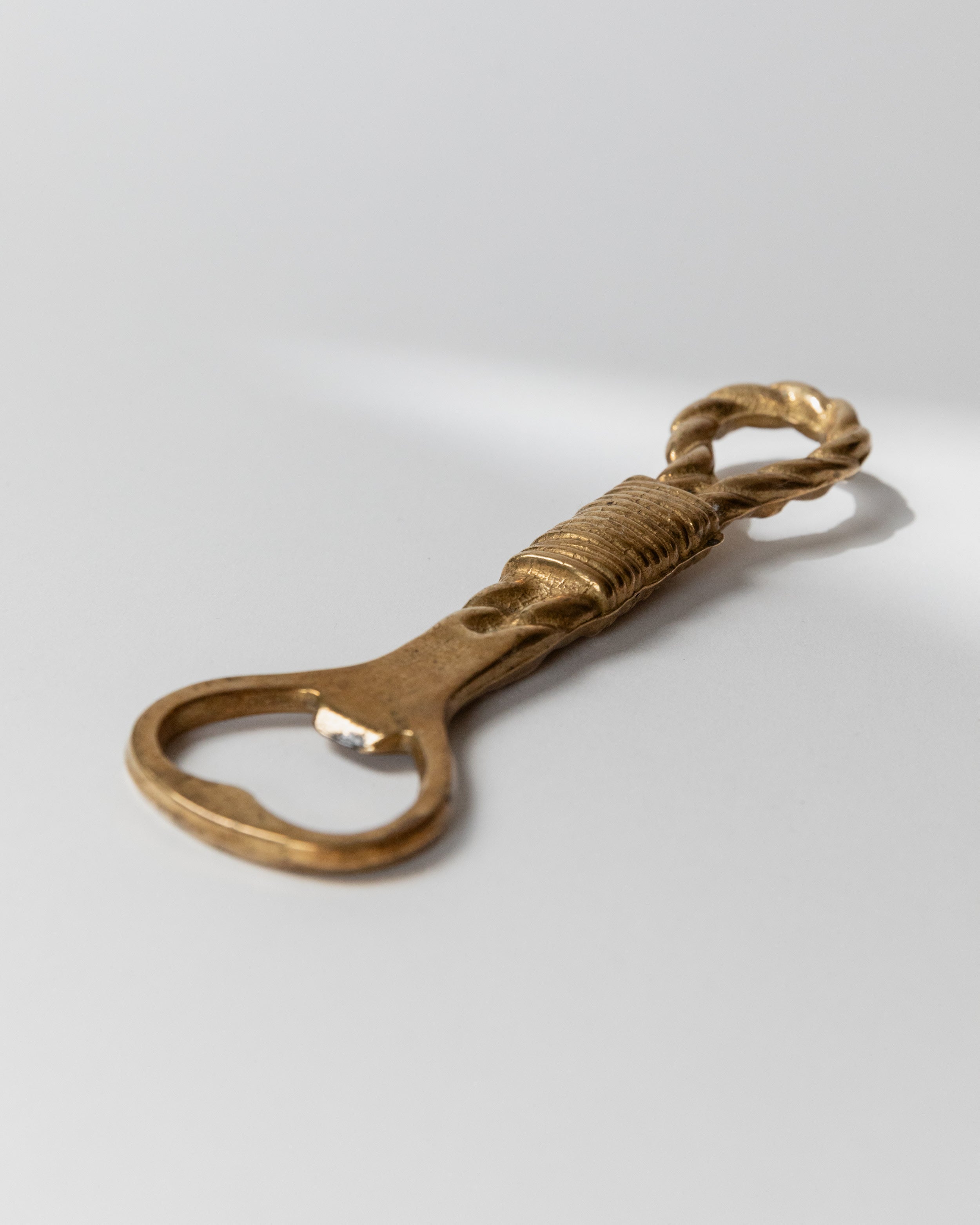 Vintage brass bottle opener with twisted rope handle detail view